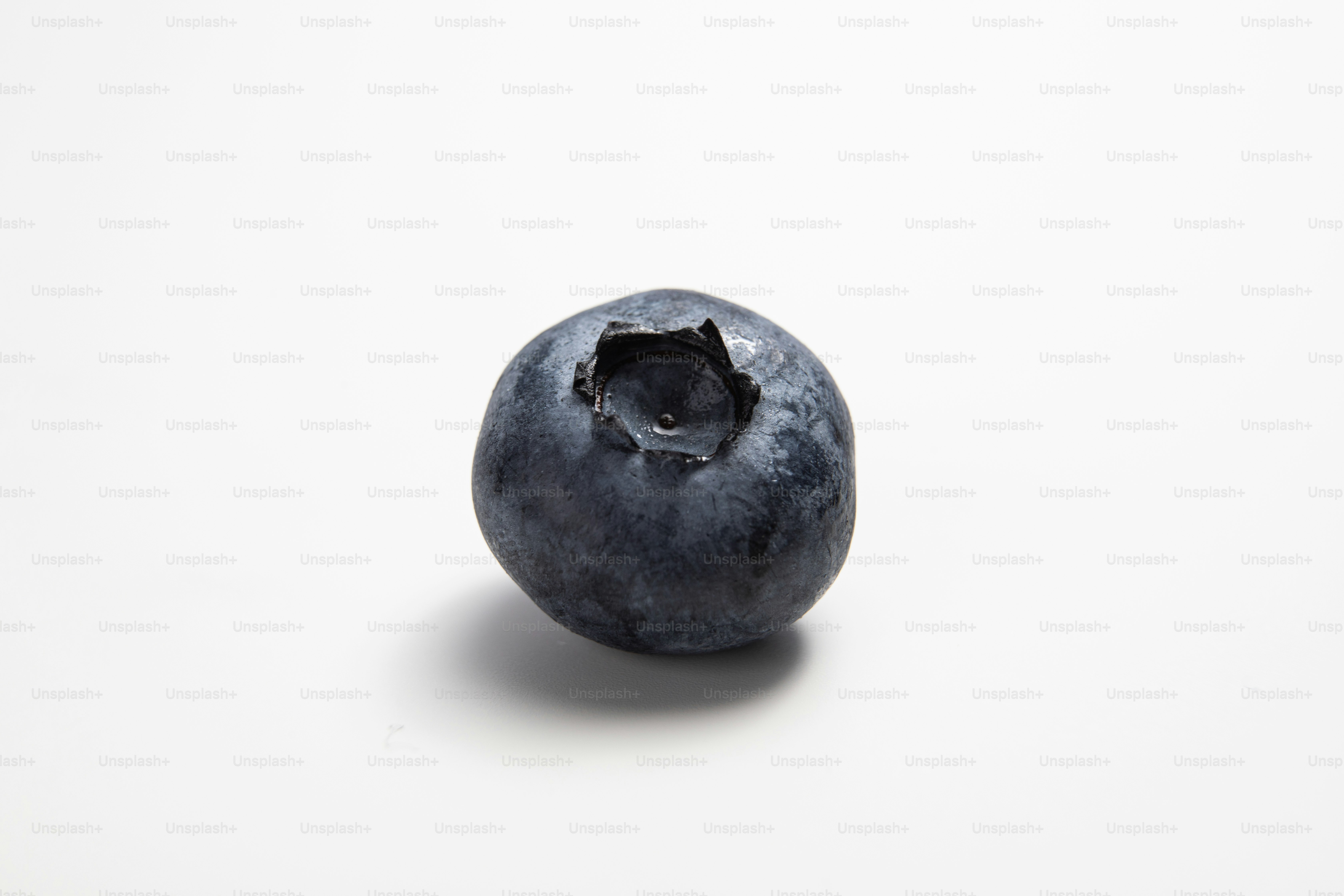 A close up of a blueberry on a white surface