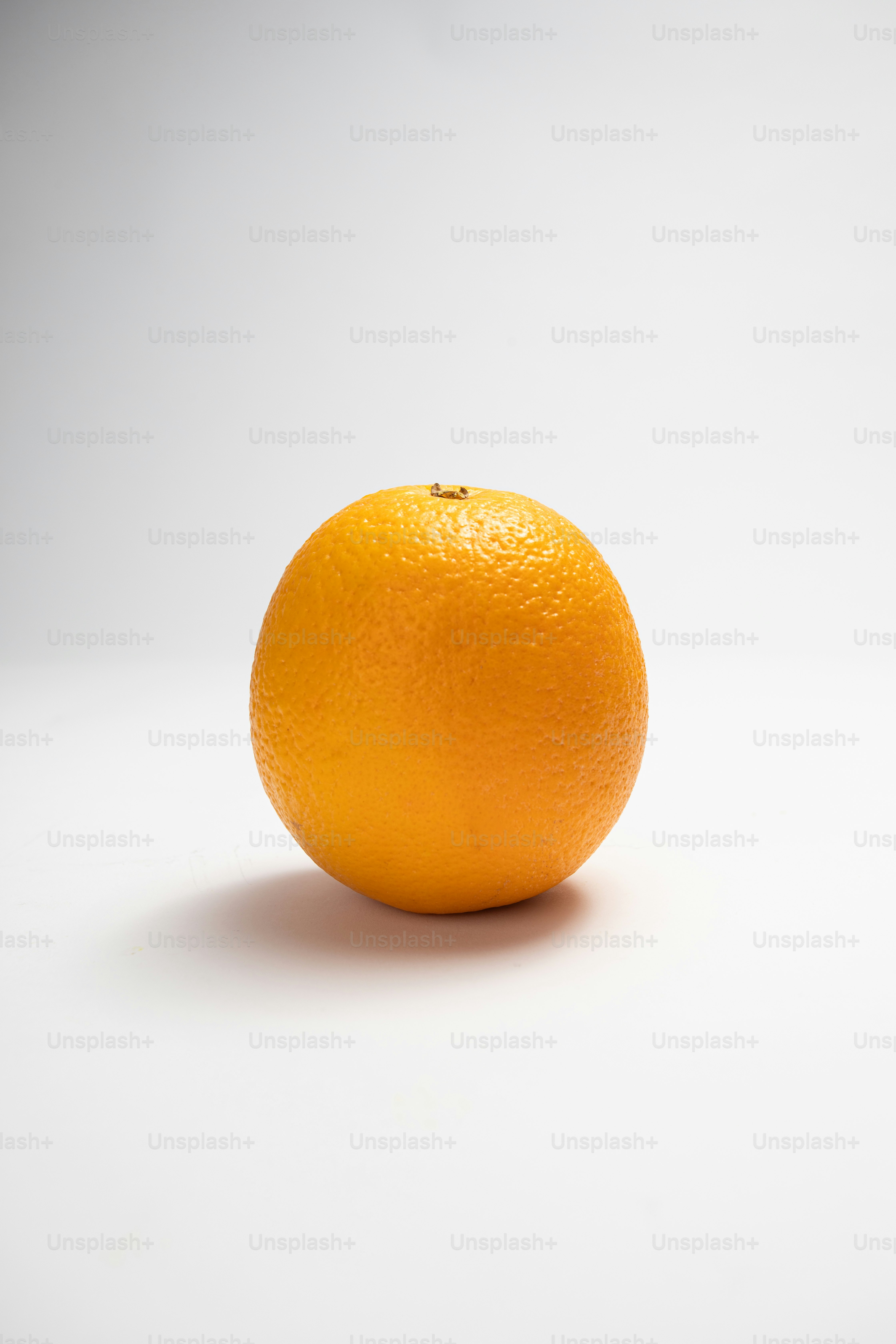 Une orange posée sur une table blanche