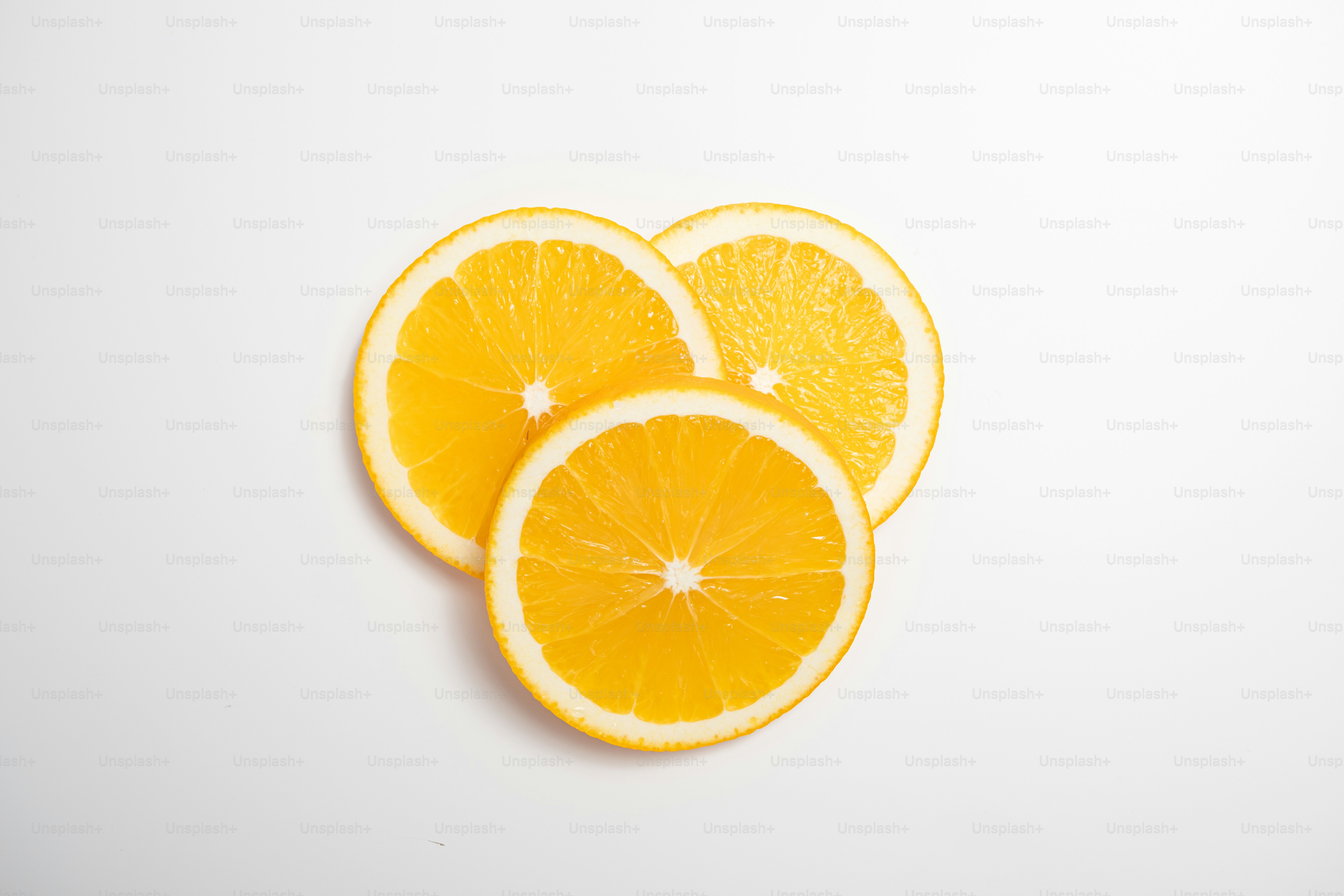 Three oranges cut in half on a white surface
