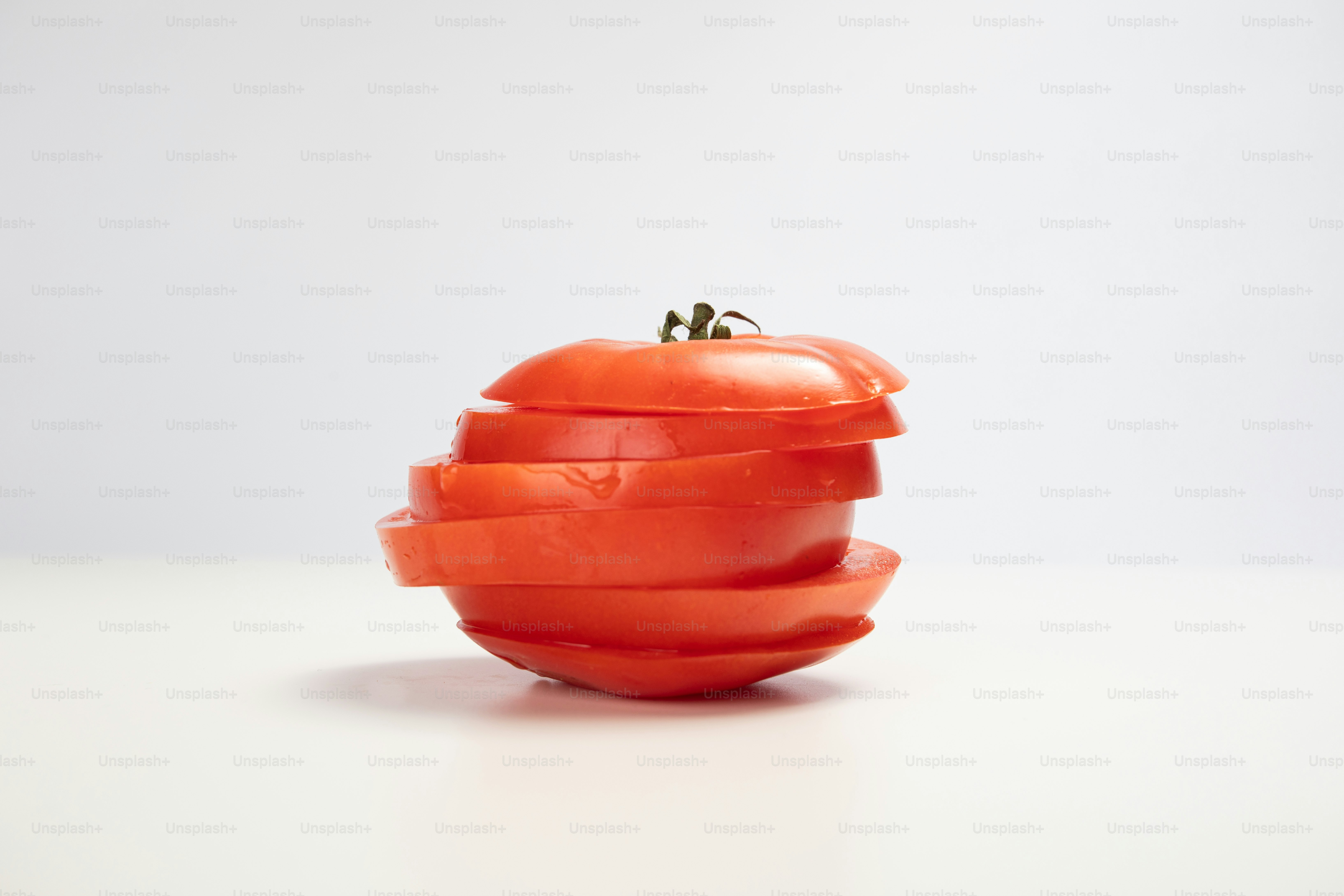 Una manzana roja cortada por la mitad sobre una superficie blanca