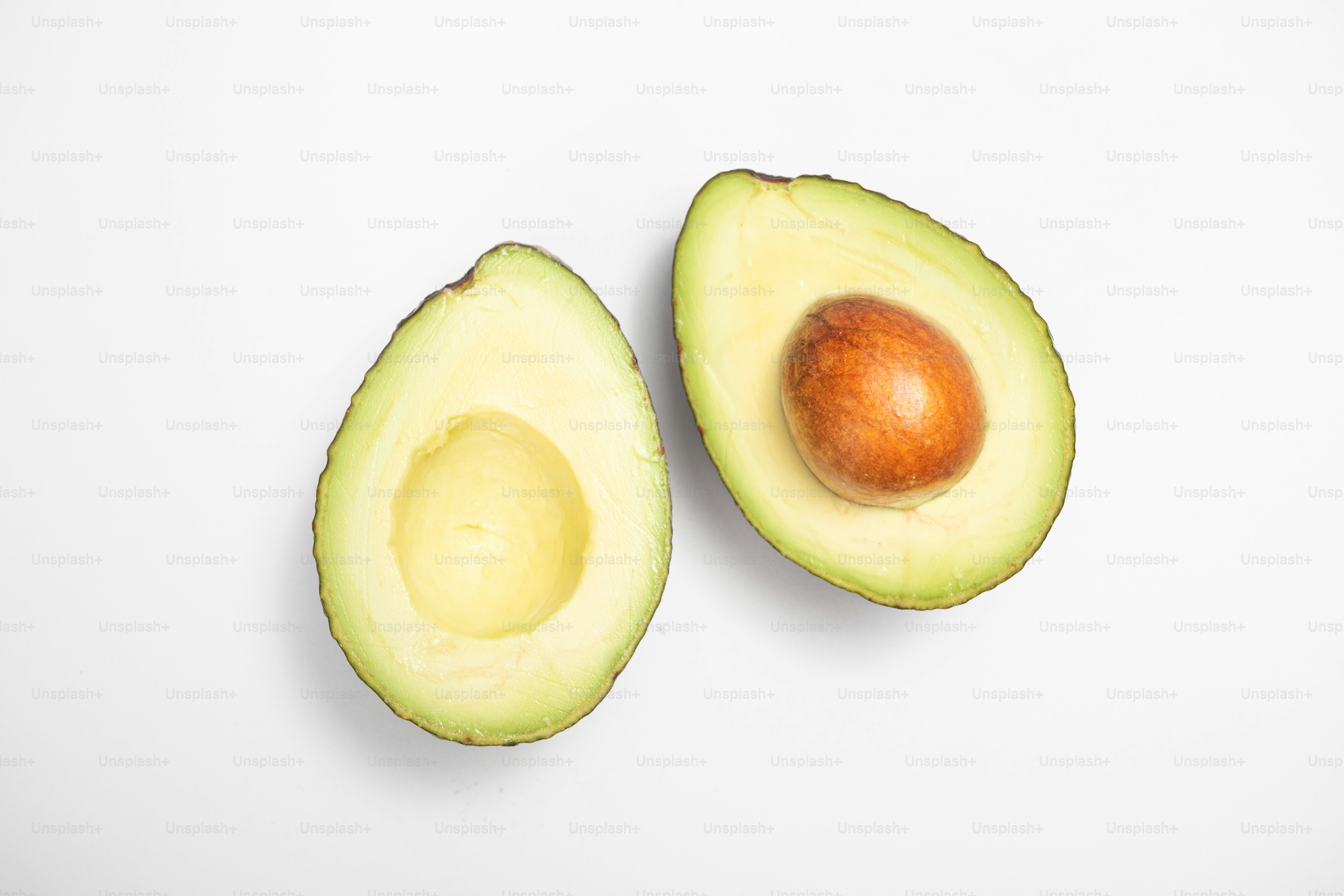 Un aguacate cortado por la mitad sobre una superficie blanca