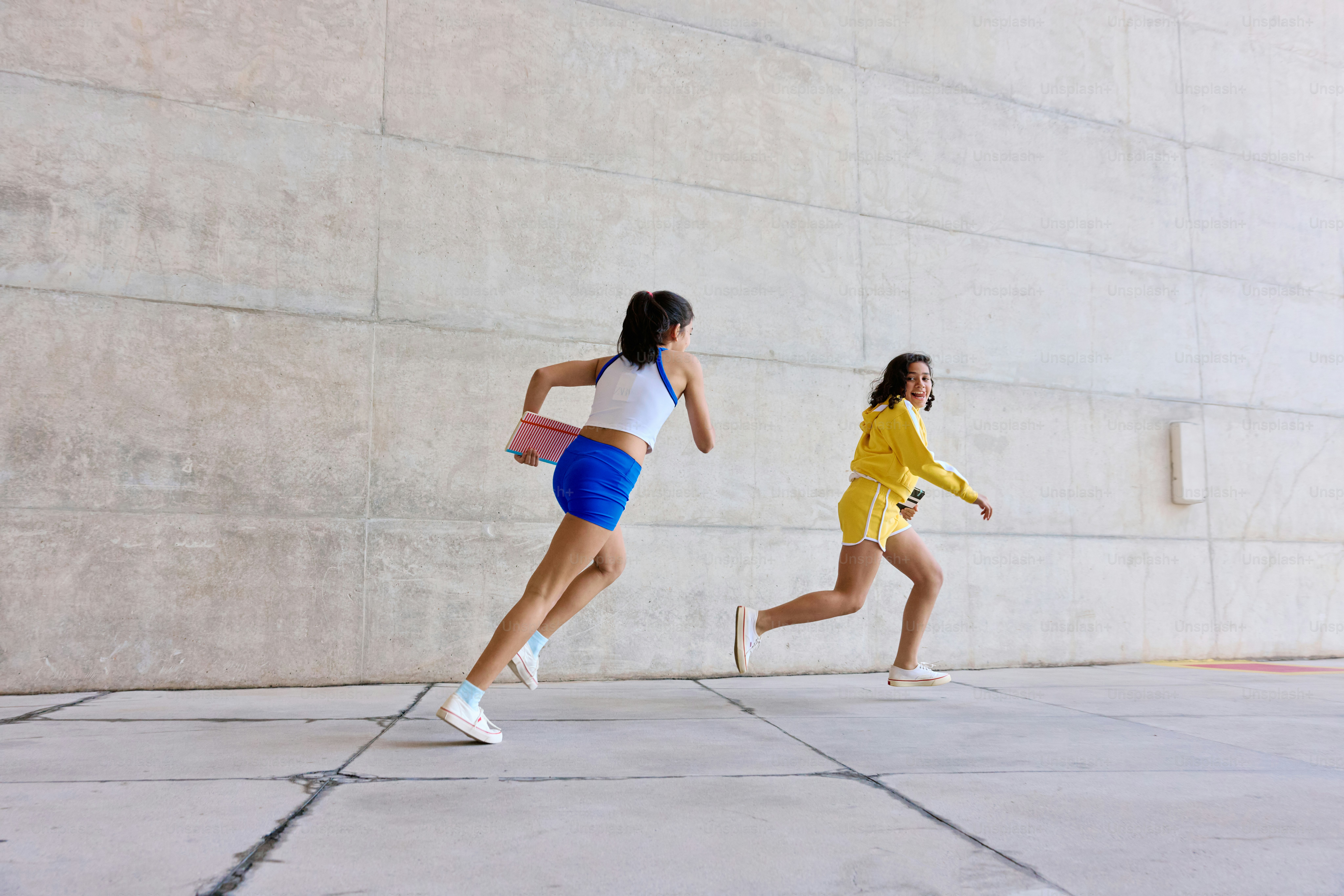 Un par de mujeres corriendo por una acera