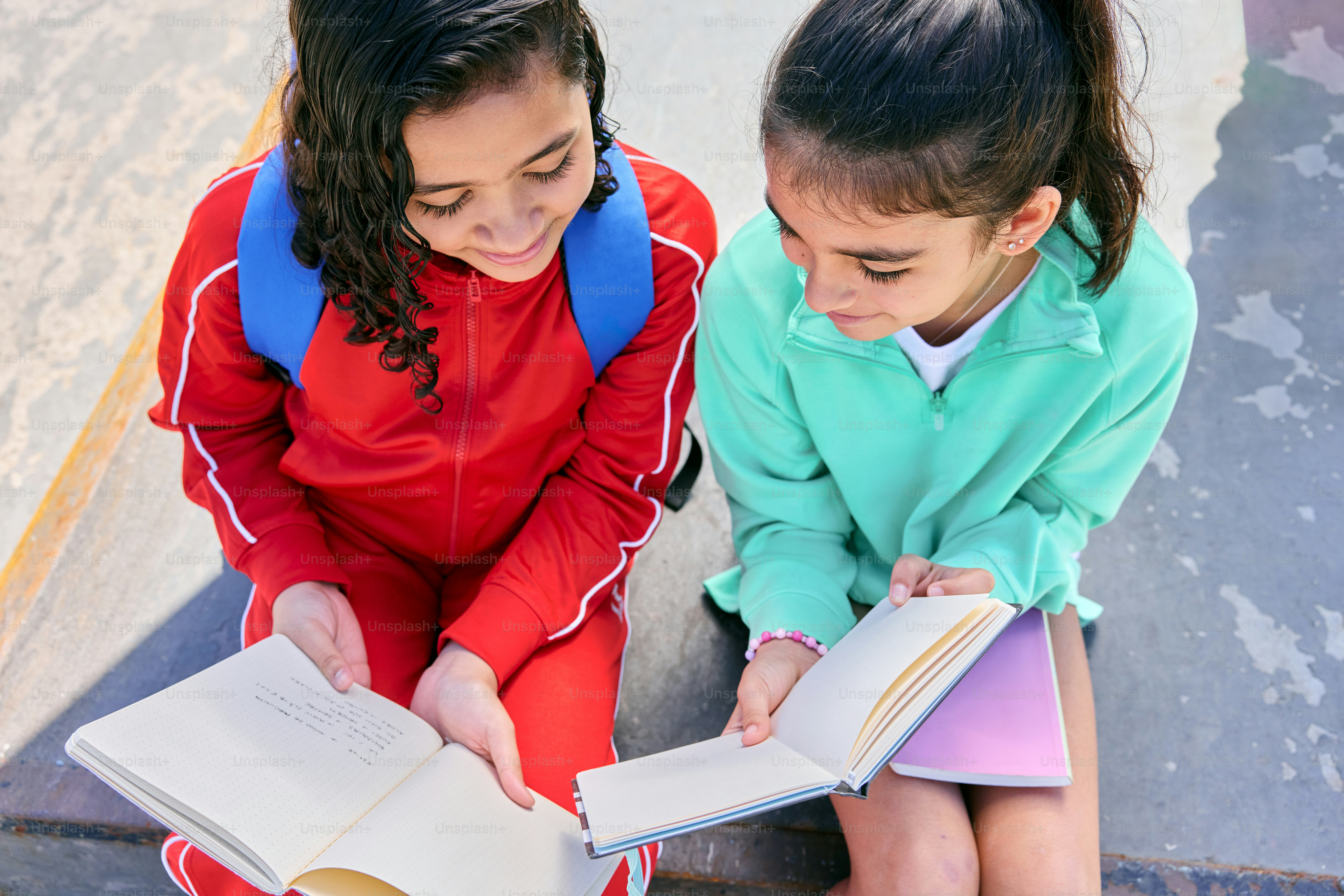 Dos muchachas jóvenes sentadas en los escalones leyendo un libro