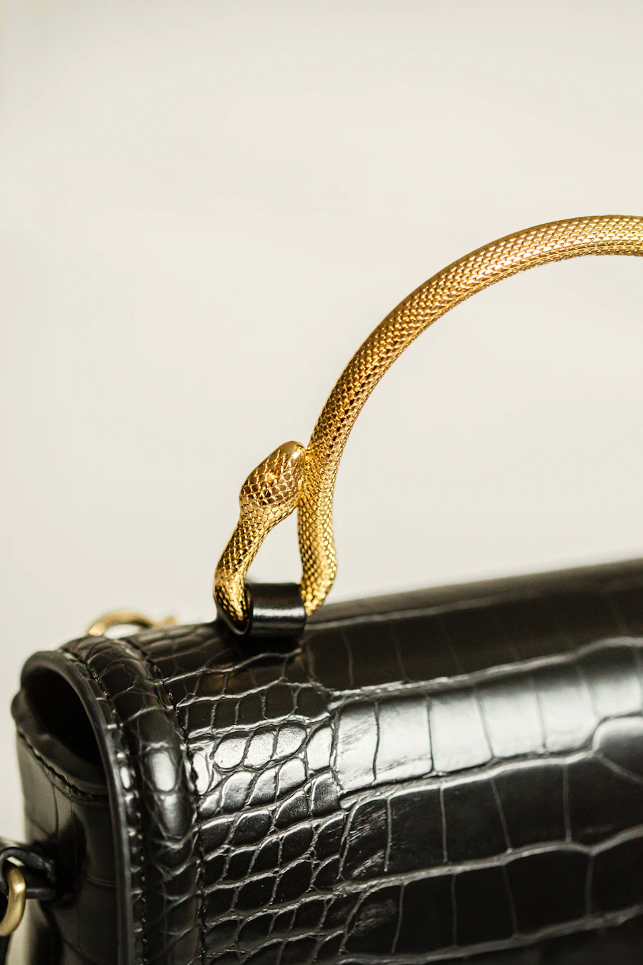 The Nocturne Clutch — a black leather purse with a gold handle on a table