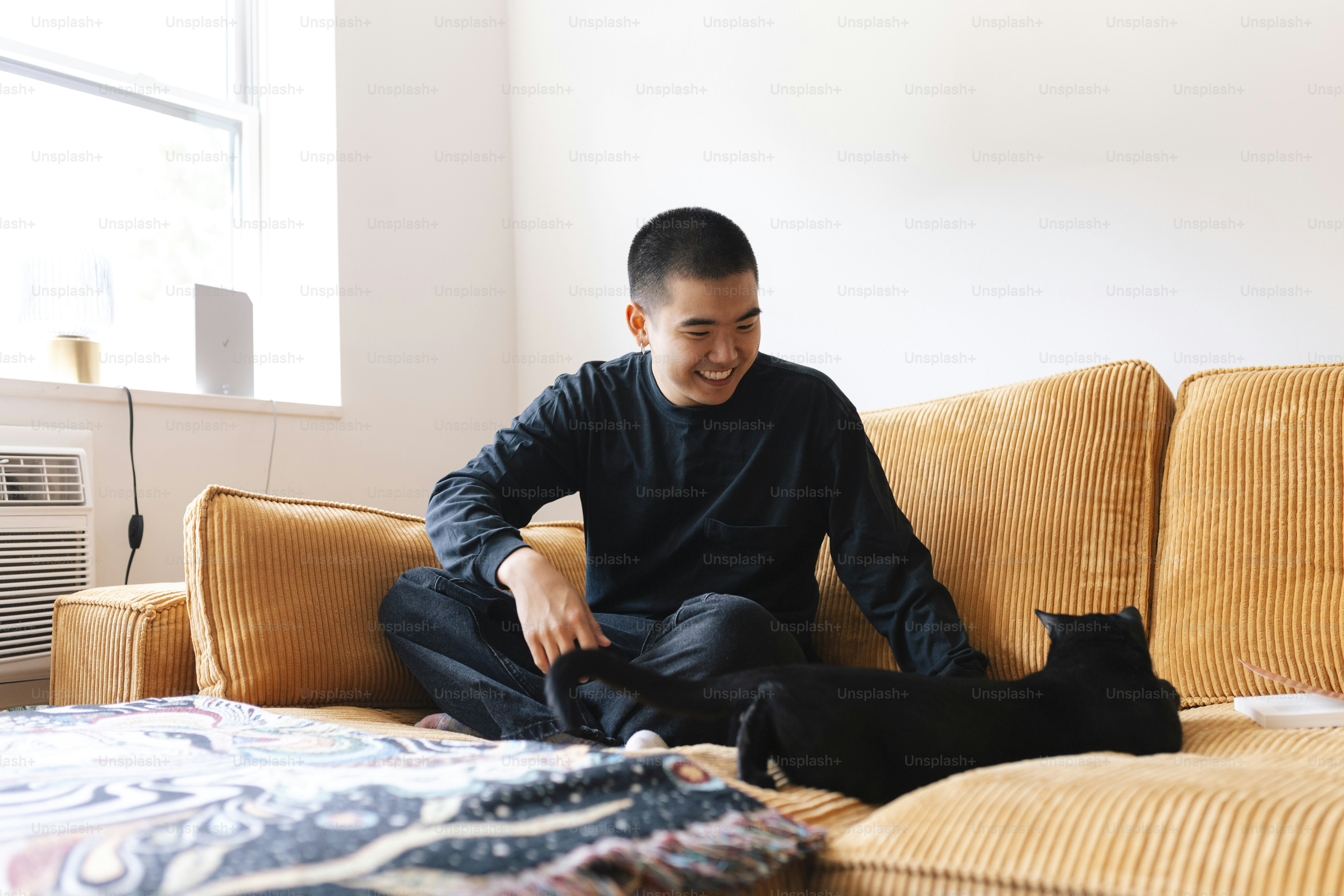 A man sitting on top of a couch next to a cat