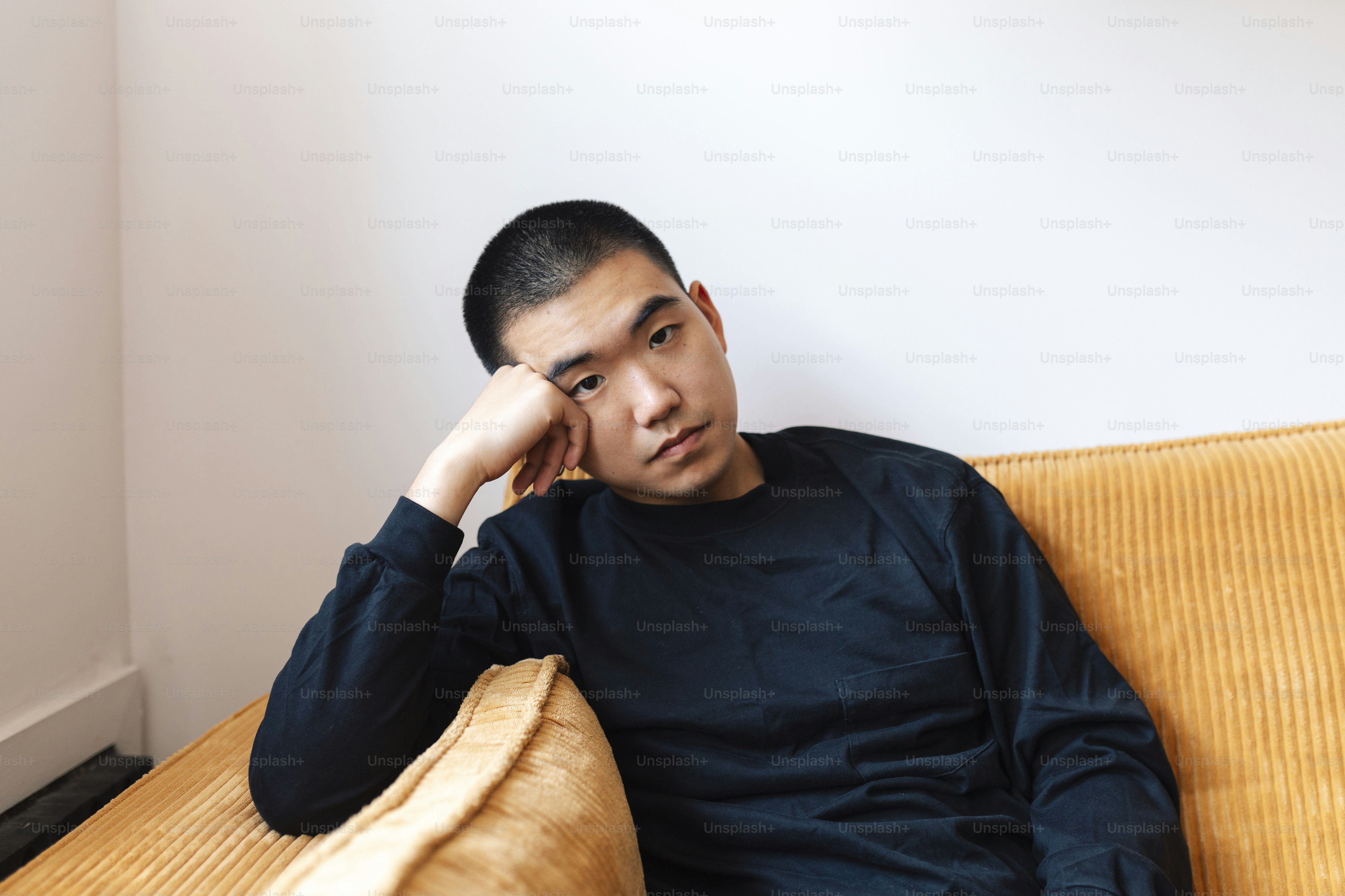 A man sitting on a couch with his hand on his head