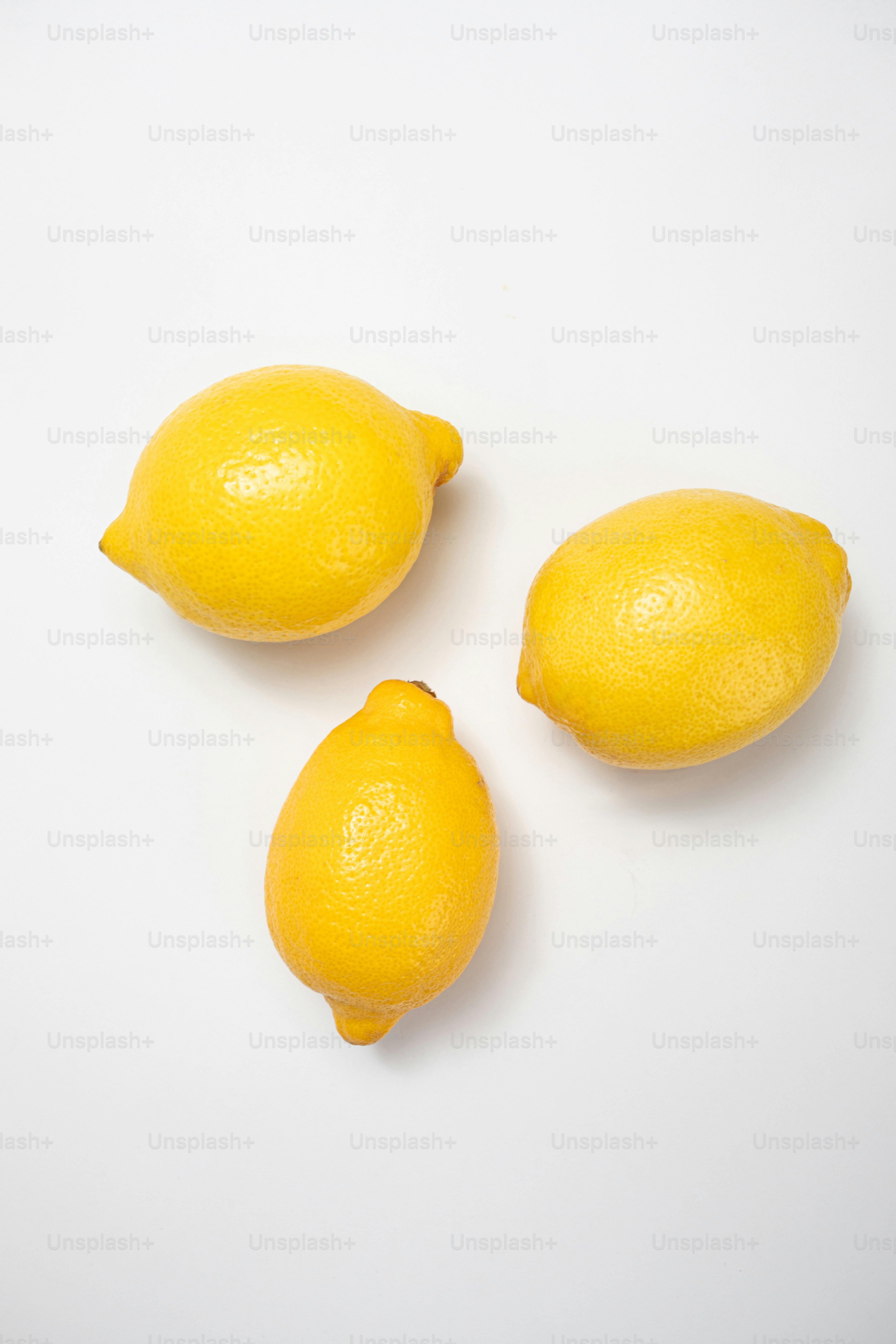 Tres limones sentados uno al lado del otro sobre una superficie blanca
