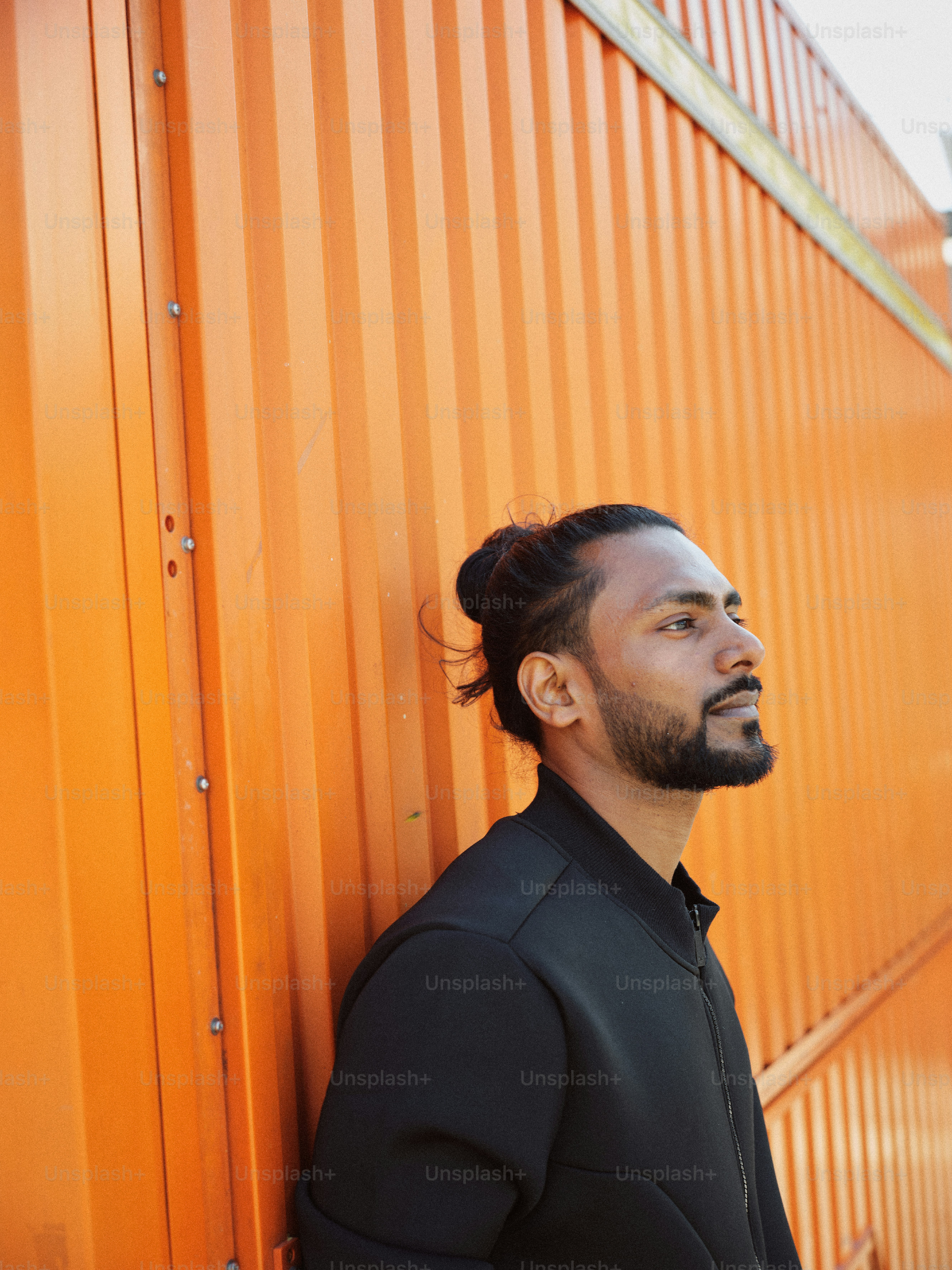 A man leaning against a wall wearing a black shirt