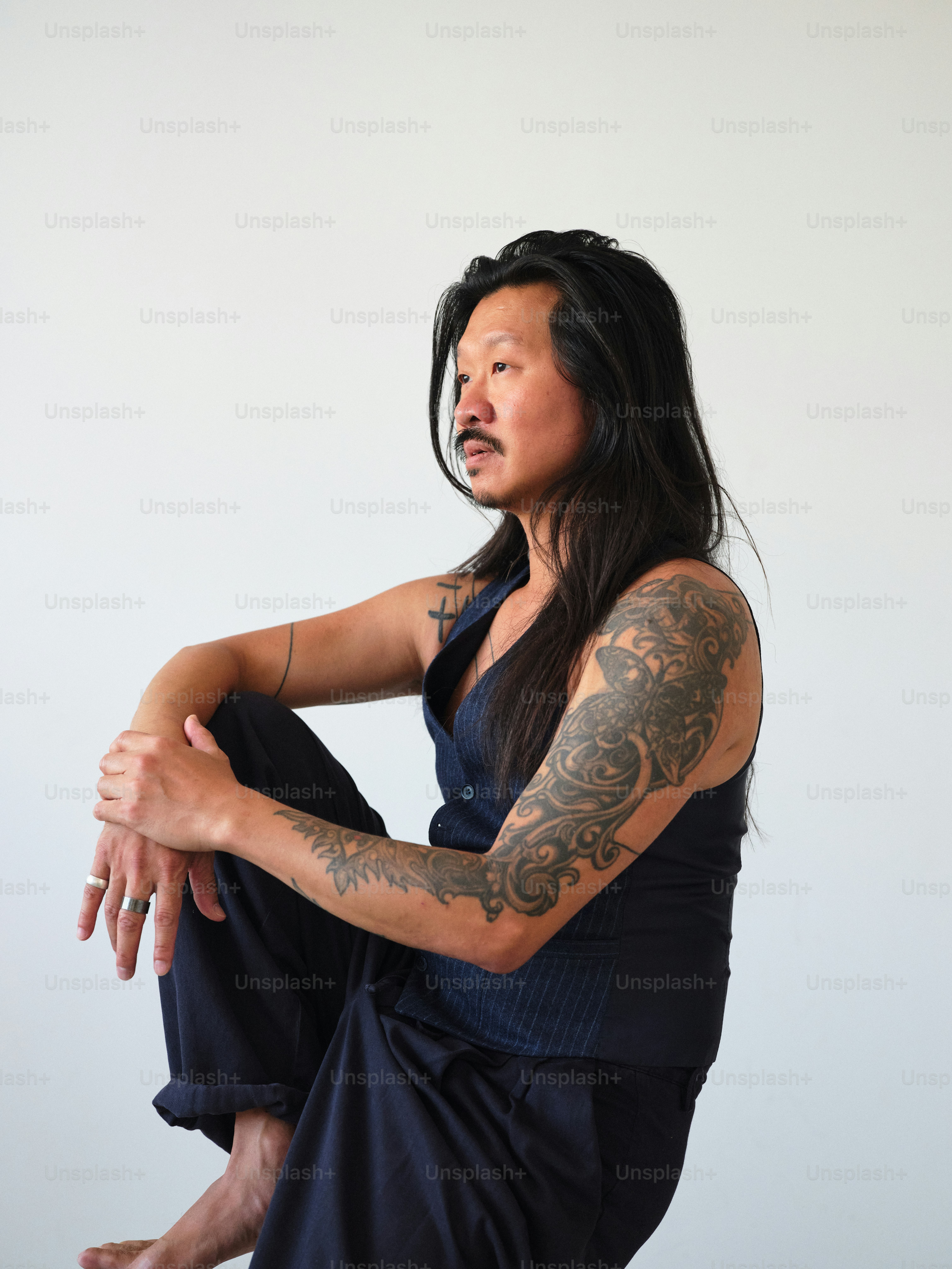 A man with tattoos sitting on the floor