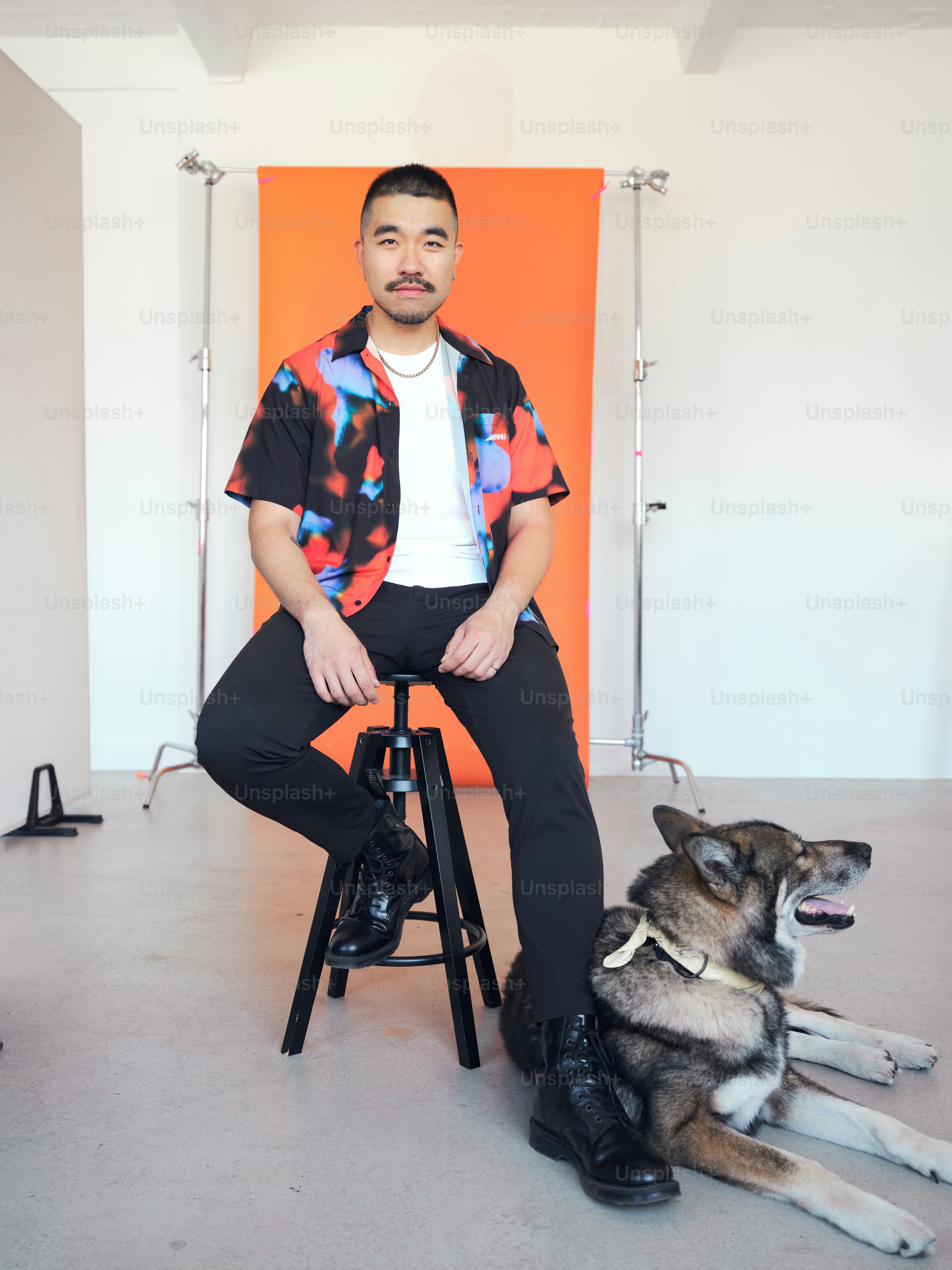 A man sitting on a stool next to a dog