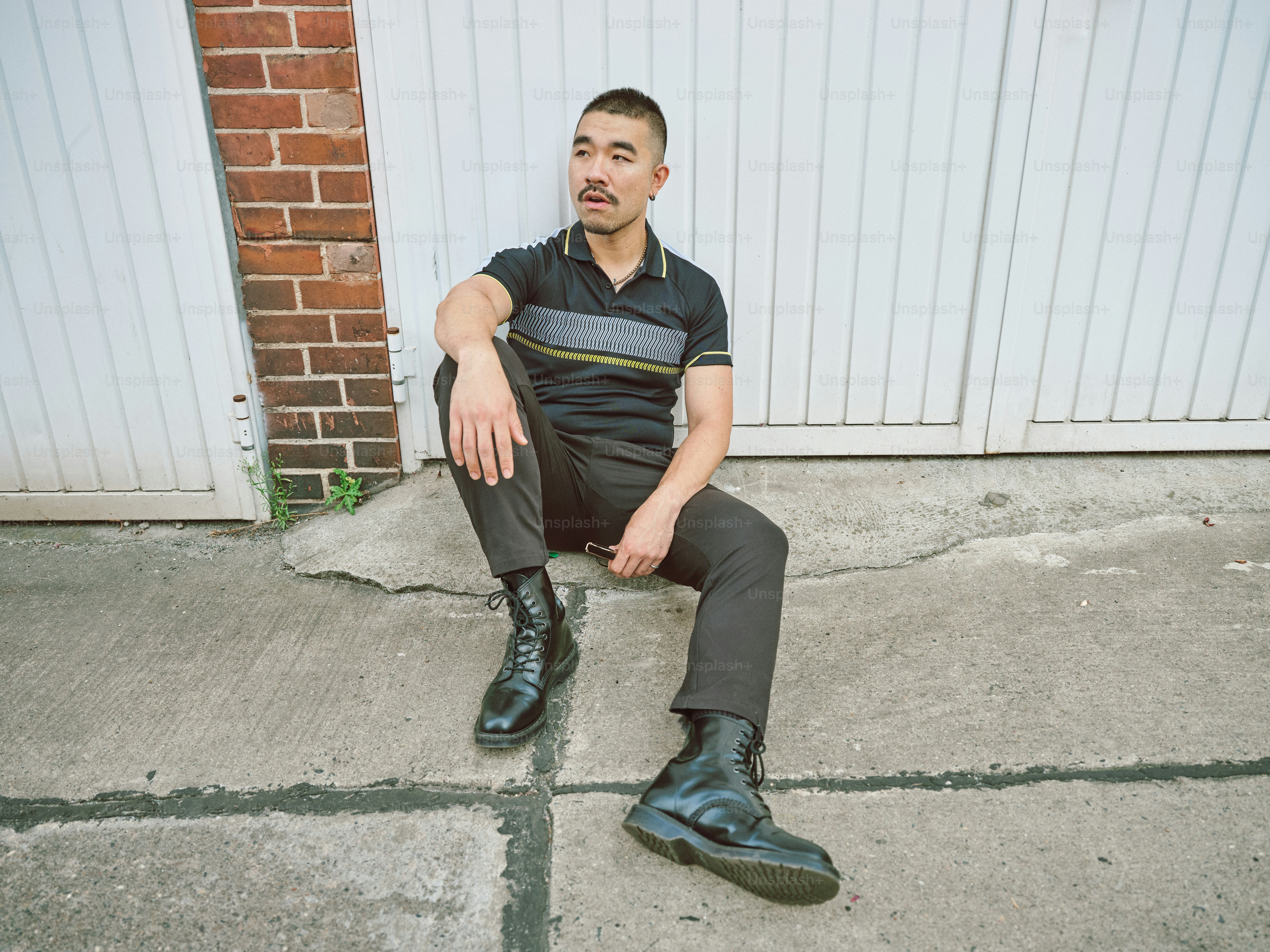 A man sitting on the sidewalk in front of a garage door