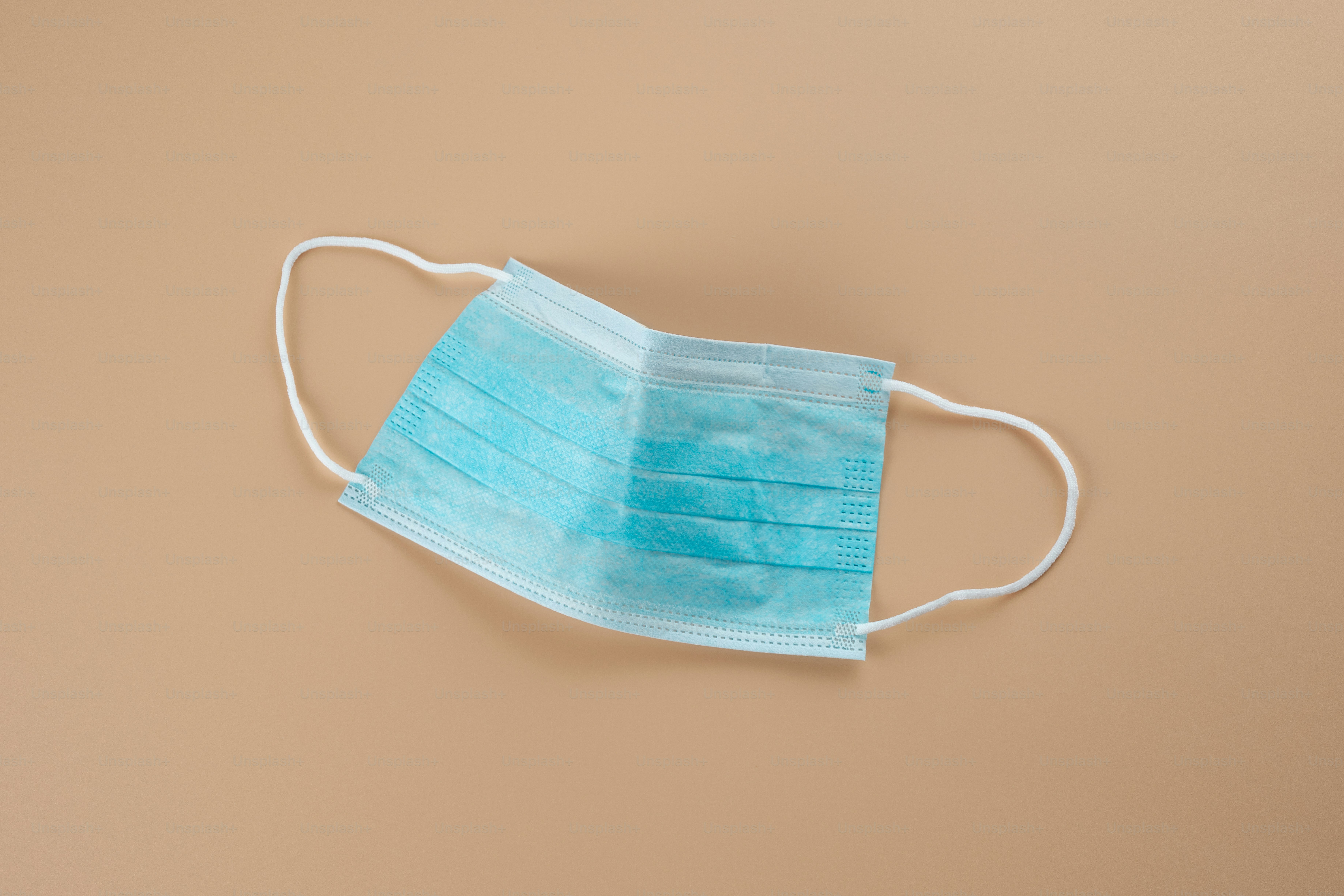 A blue face mask on a tan background
