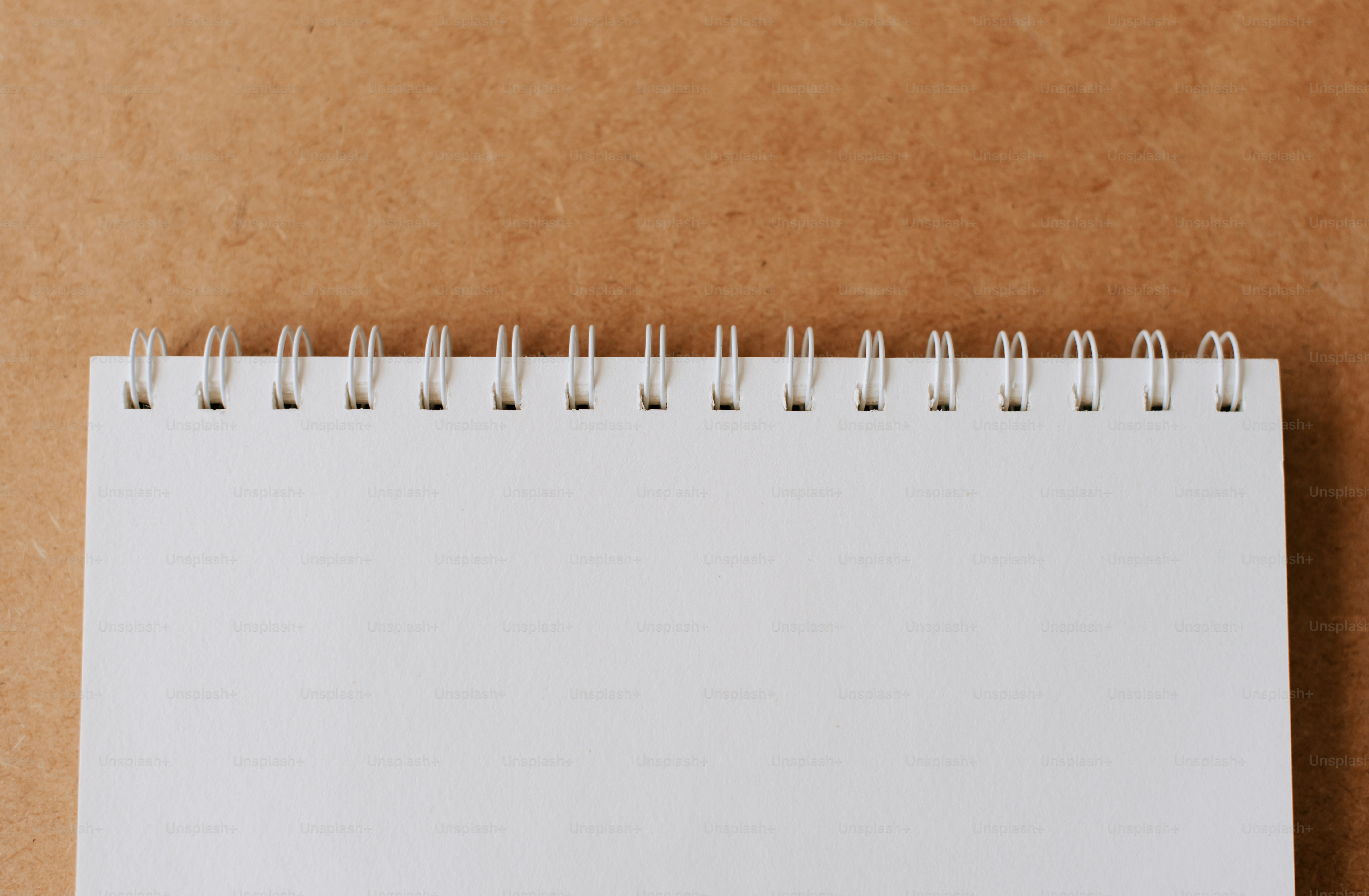 A spiral notebook with a blank page on a brown background