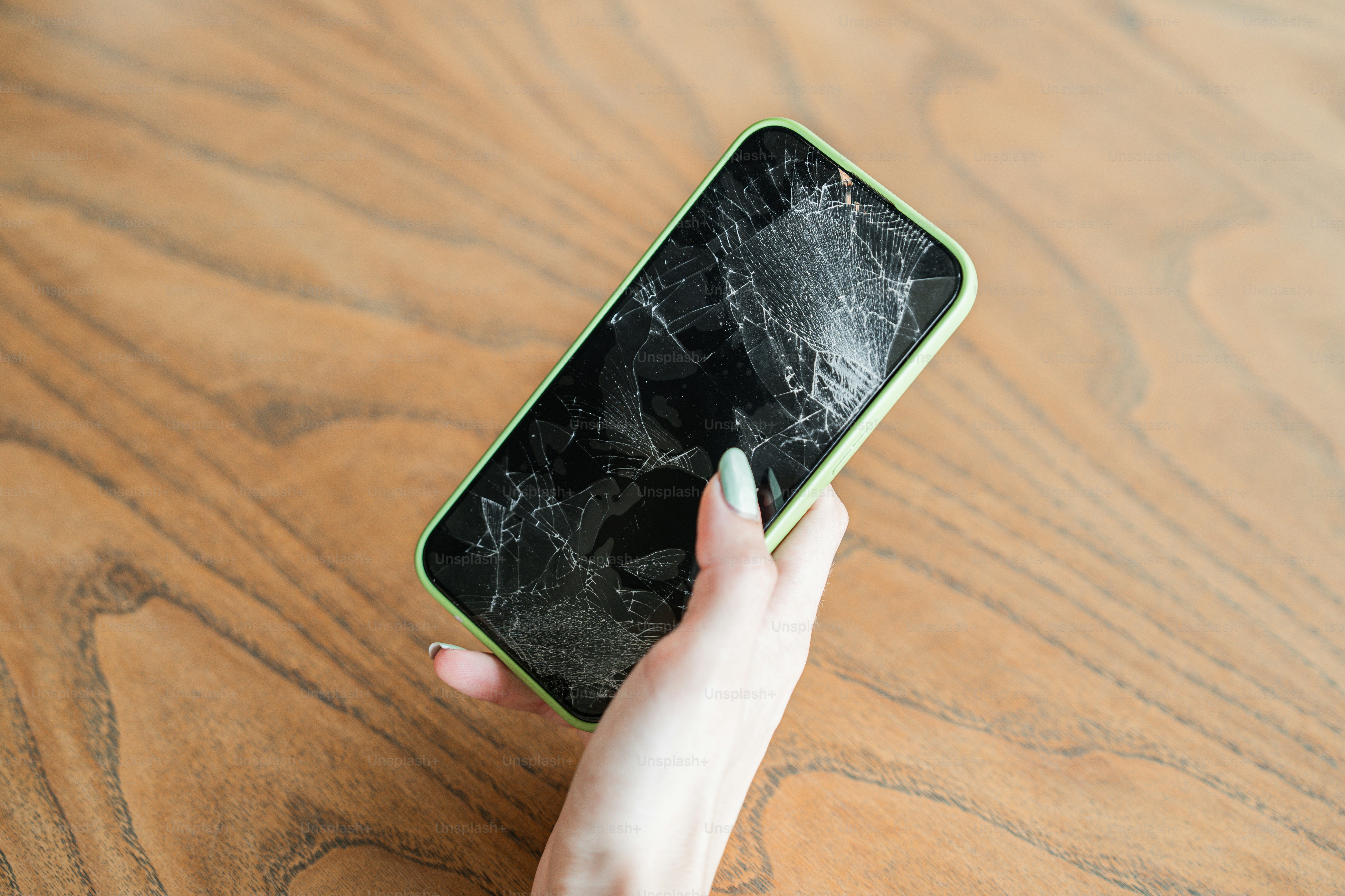 Una persona che tiene in mano un telefono cellulare con uno schermo rotto