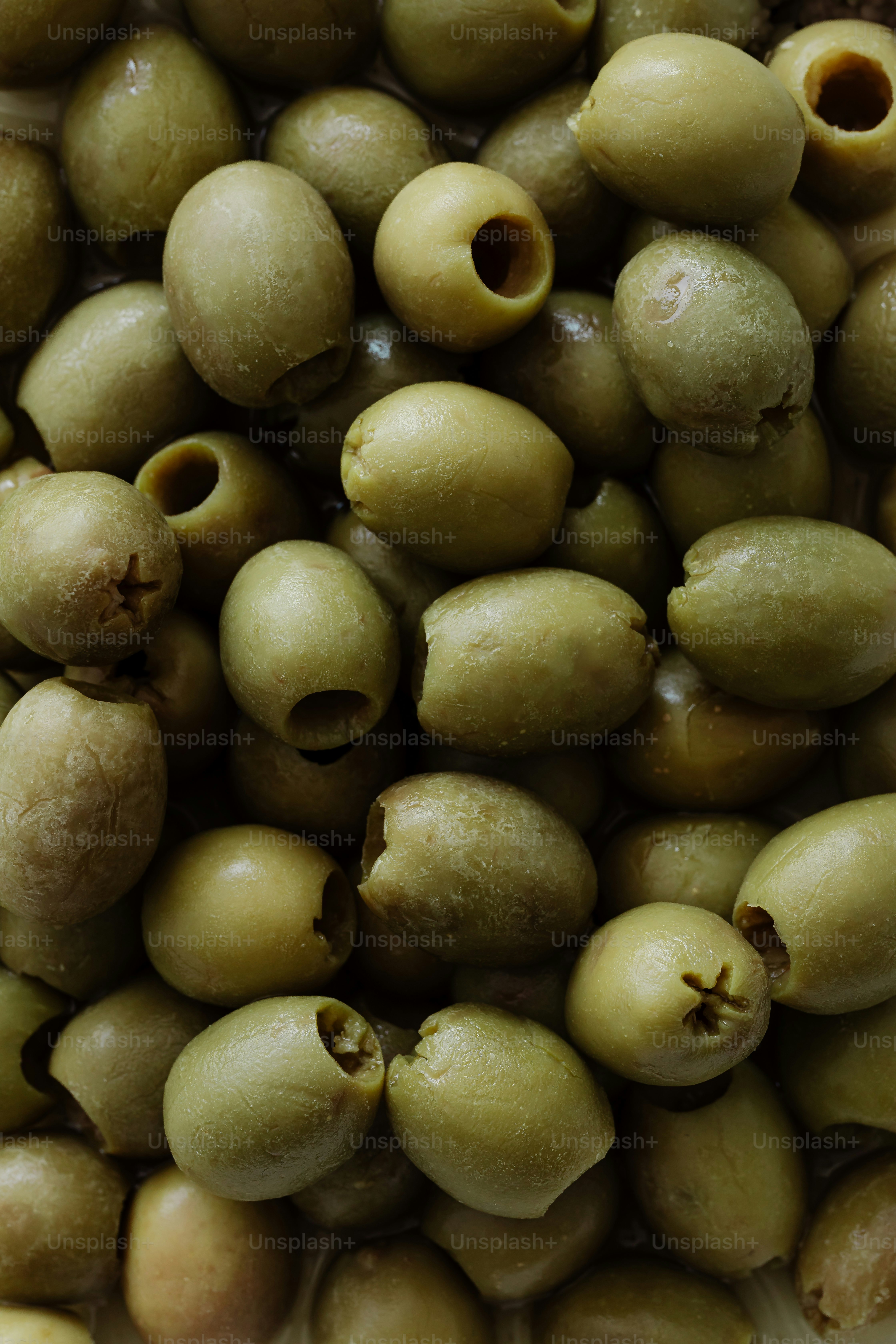 A pile of green olives sitting next to each other
