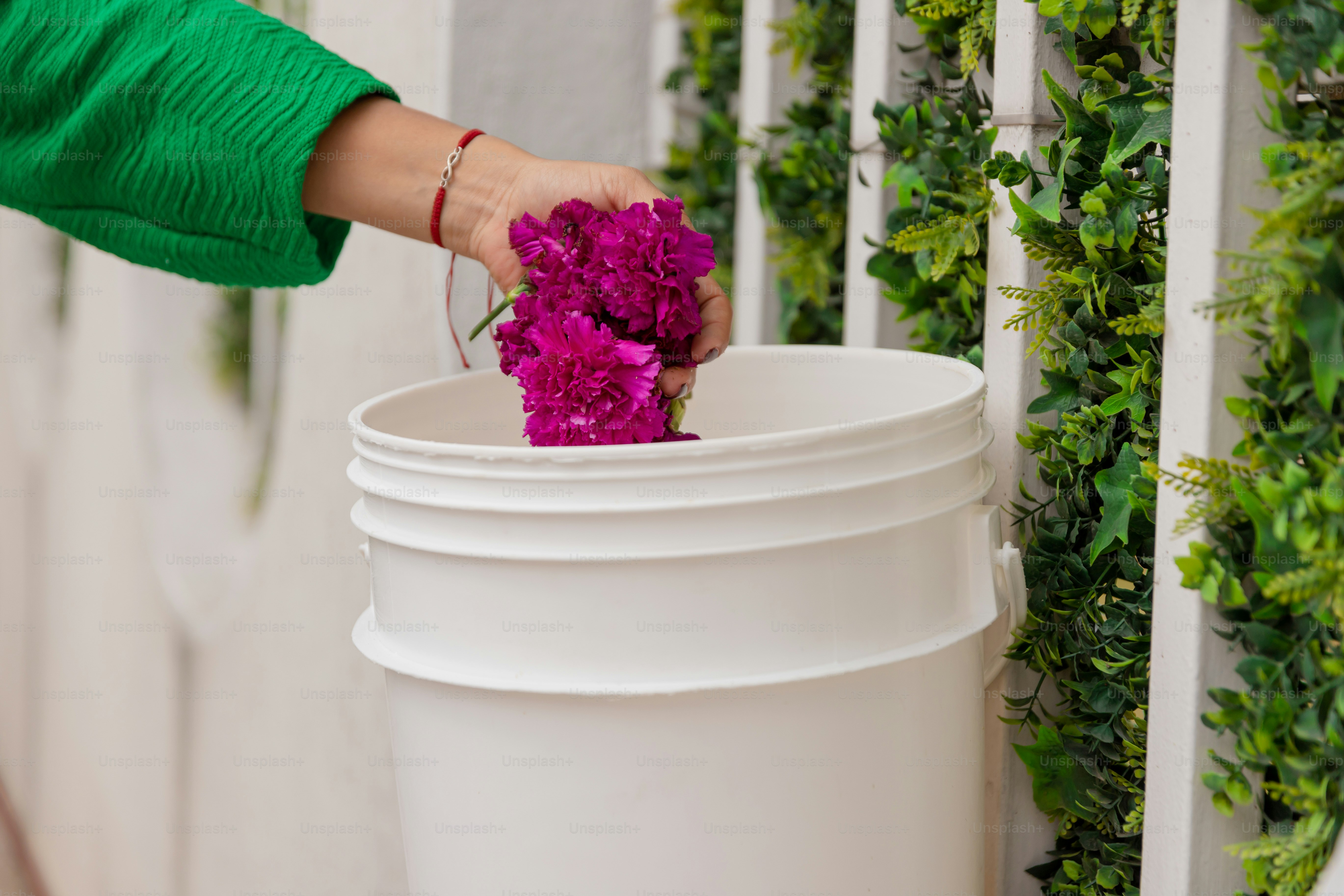 A person putting flowers into a white trash can