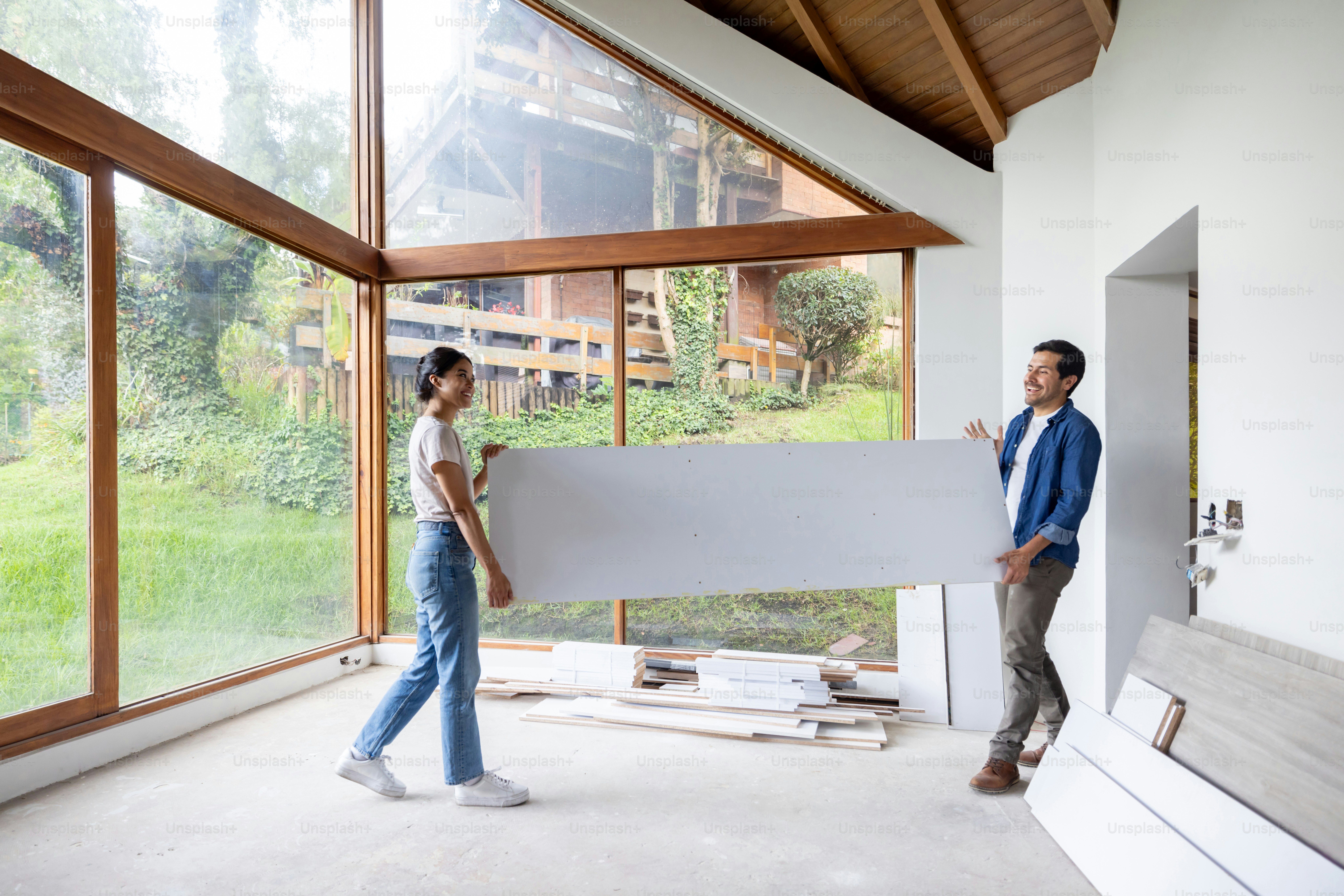 Happy Latin American couple moving house and carrying furniture while smiling