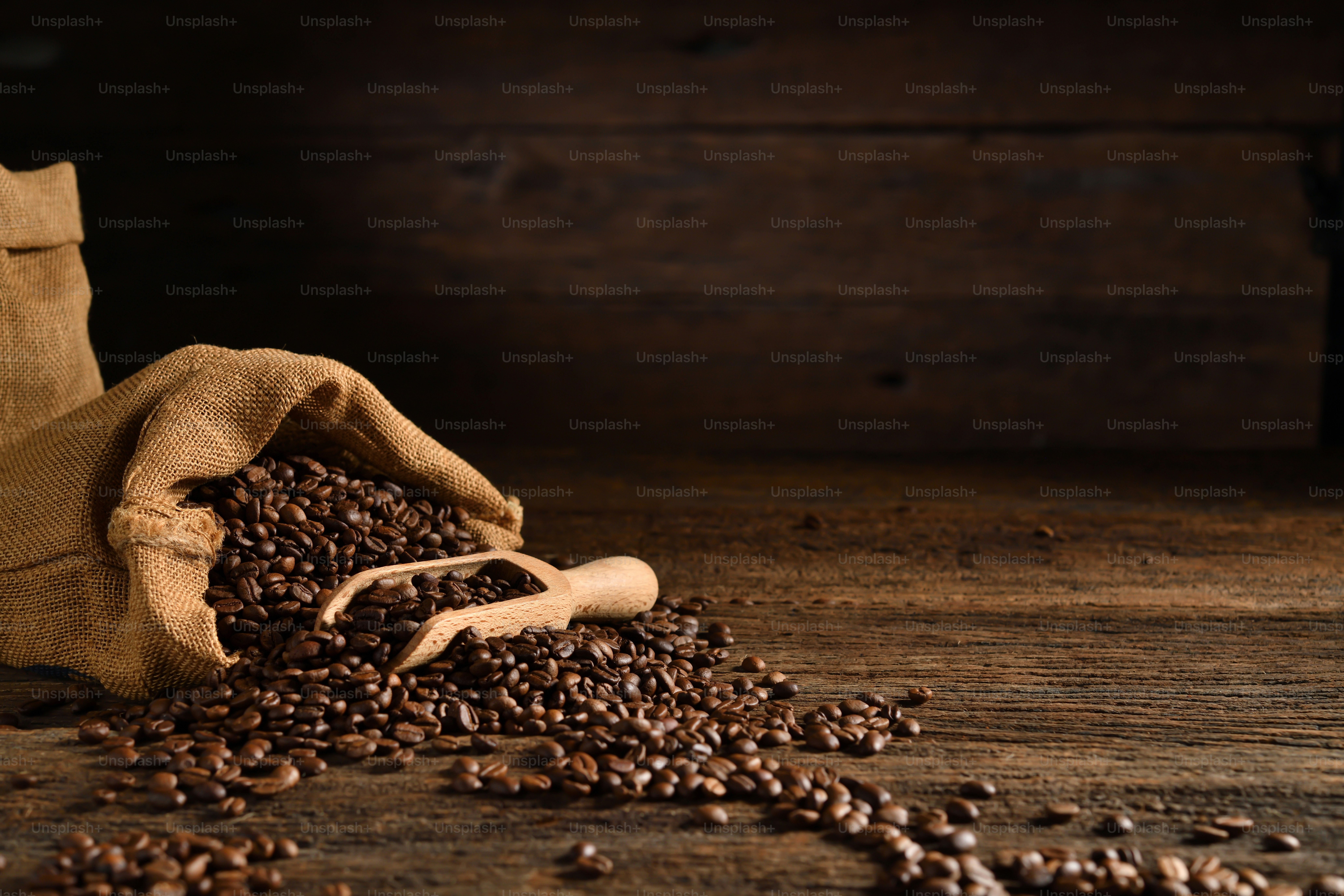 Roasted coffee beans in burlap sack on wooden table