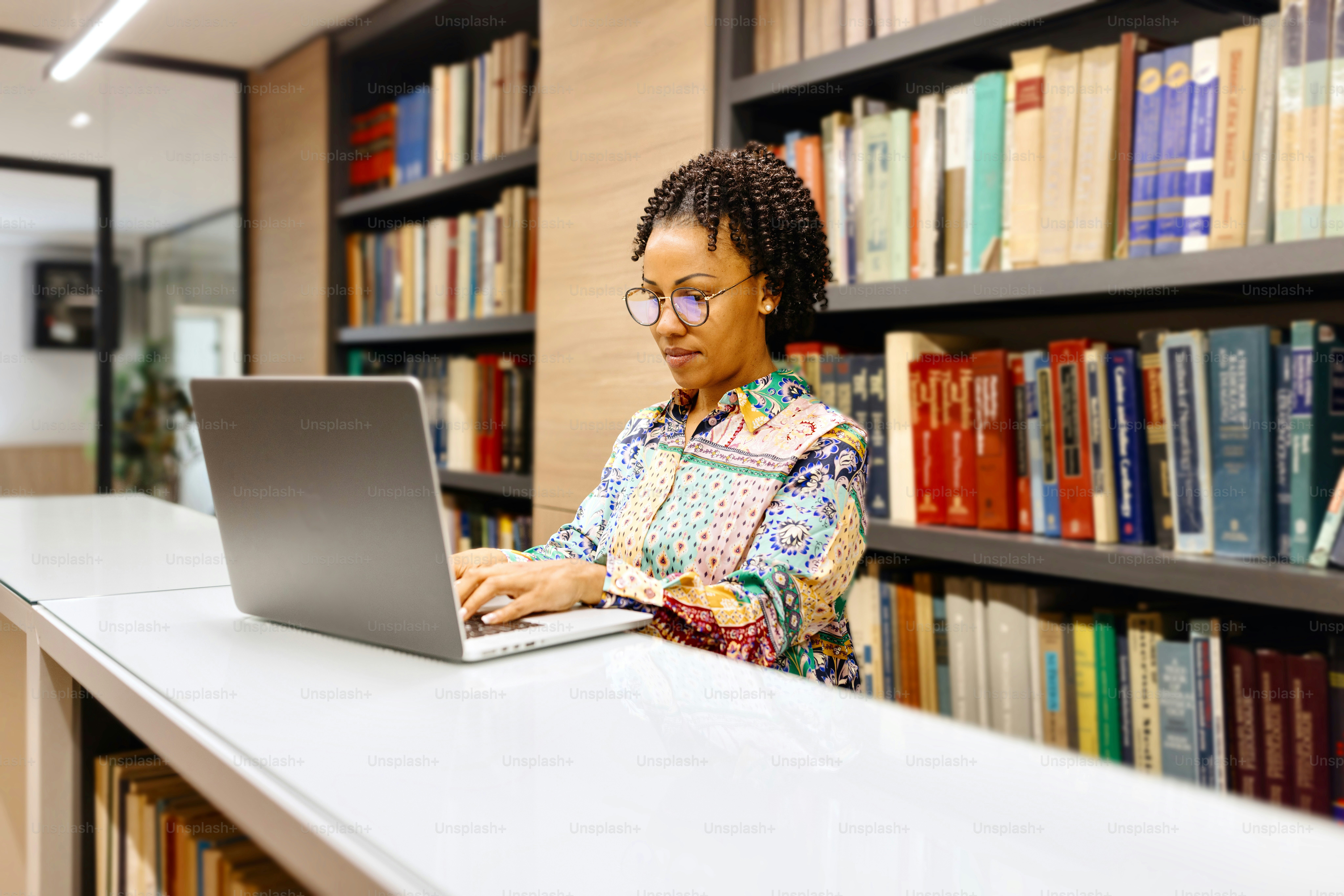 Productive professor working on a laptop at the library