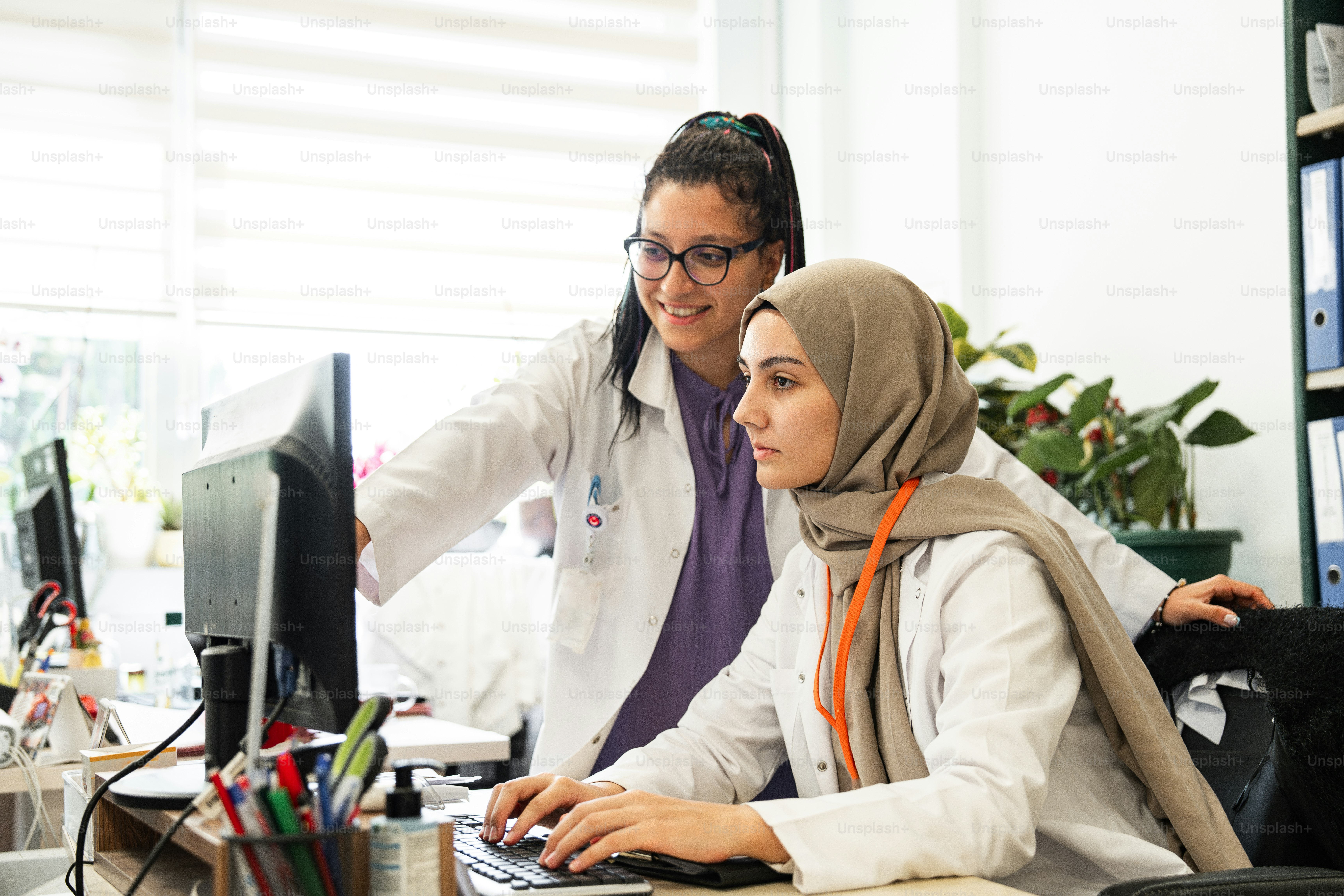 Un par de mujeres sentadas en un escritorio frente a una computadora