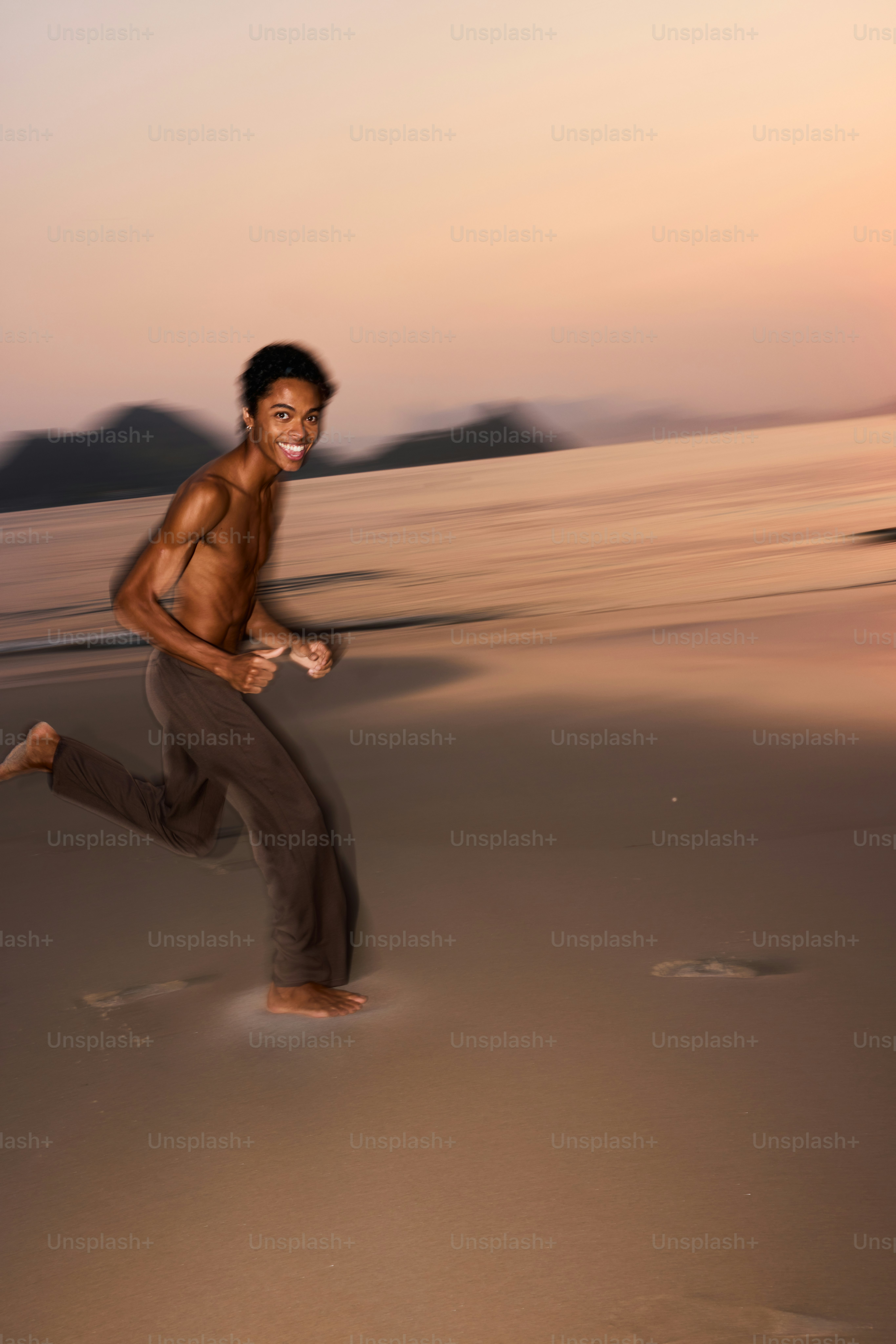 夕暮れ時のビーチを走る男性