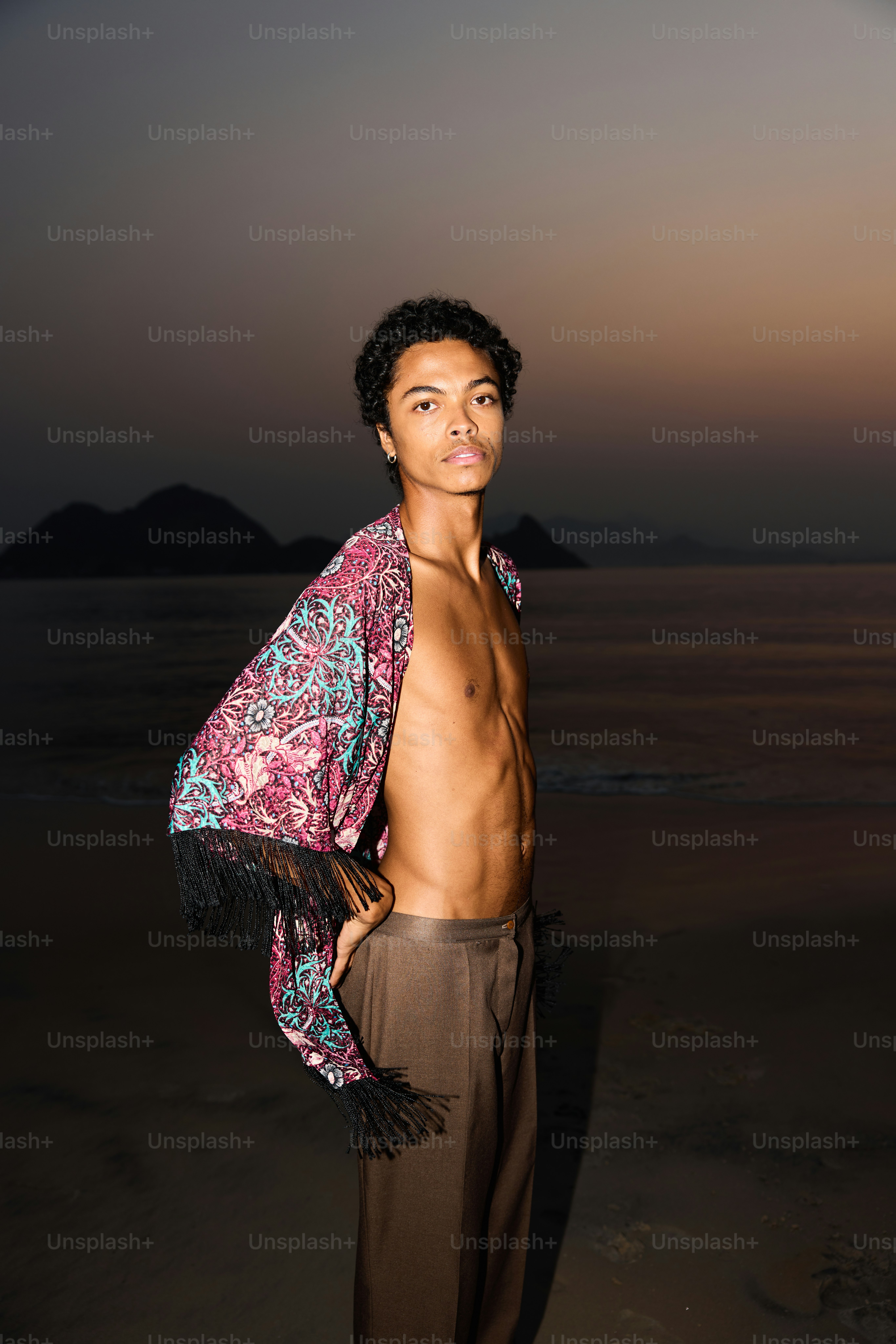 A man standing on top of a beach next to the ocean photo – Portraits ...