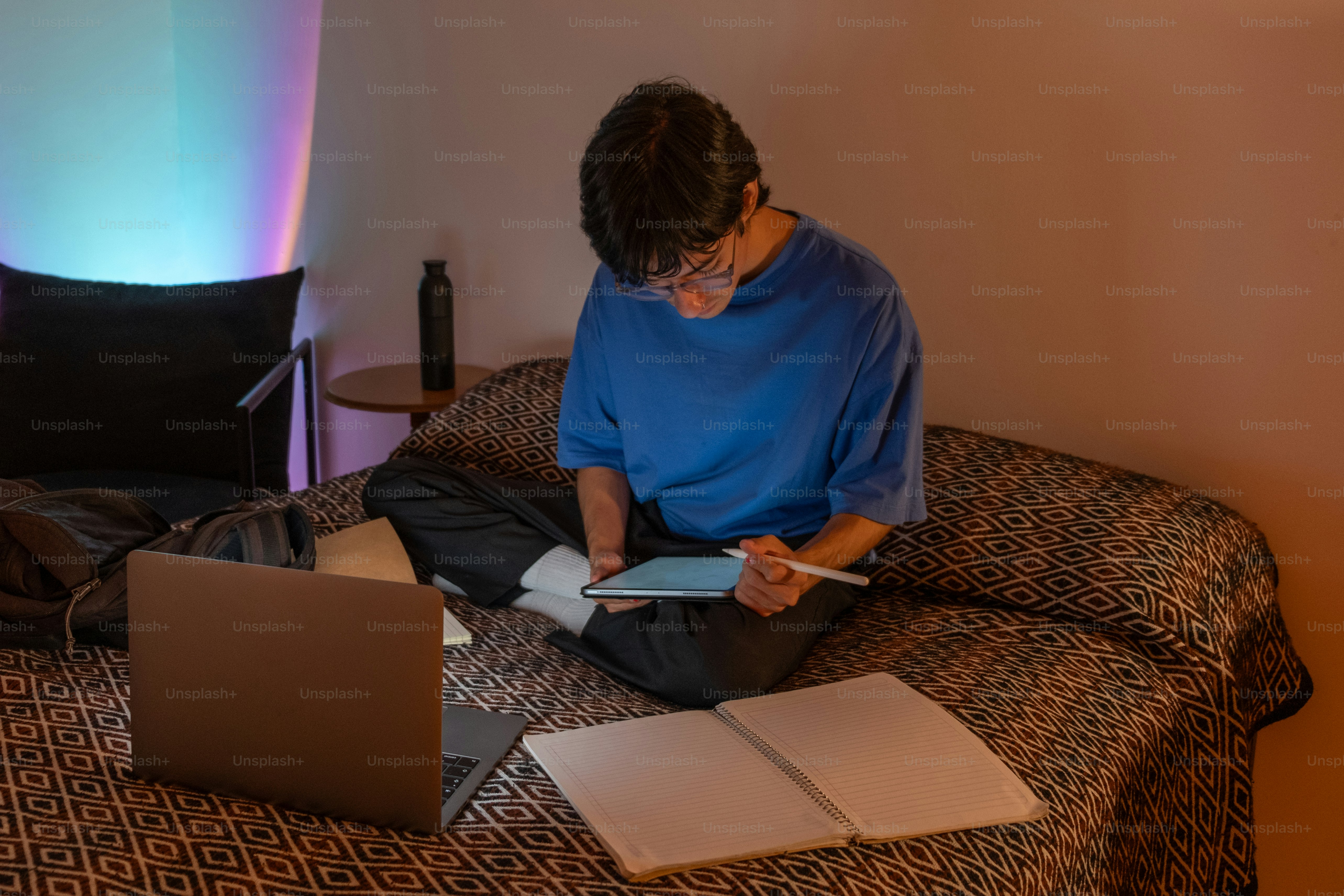 A man sitting on a bed using a laptop computer
