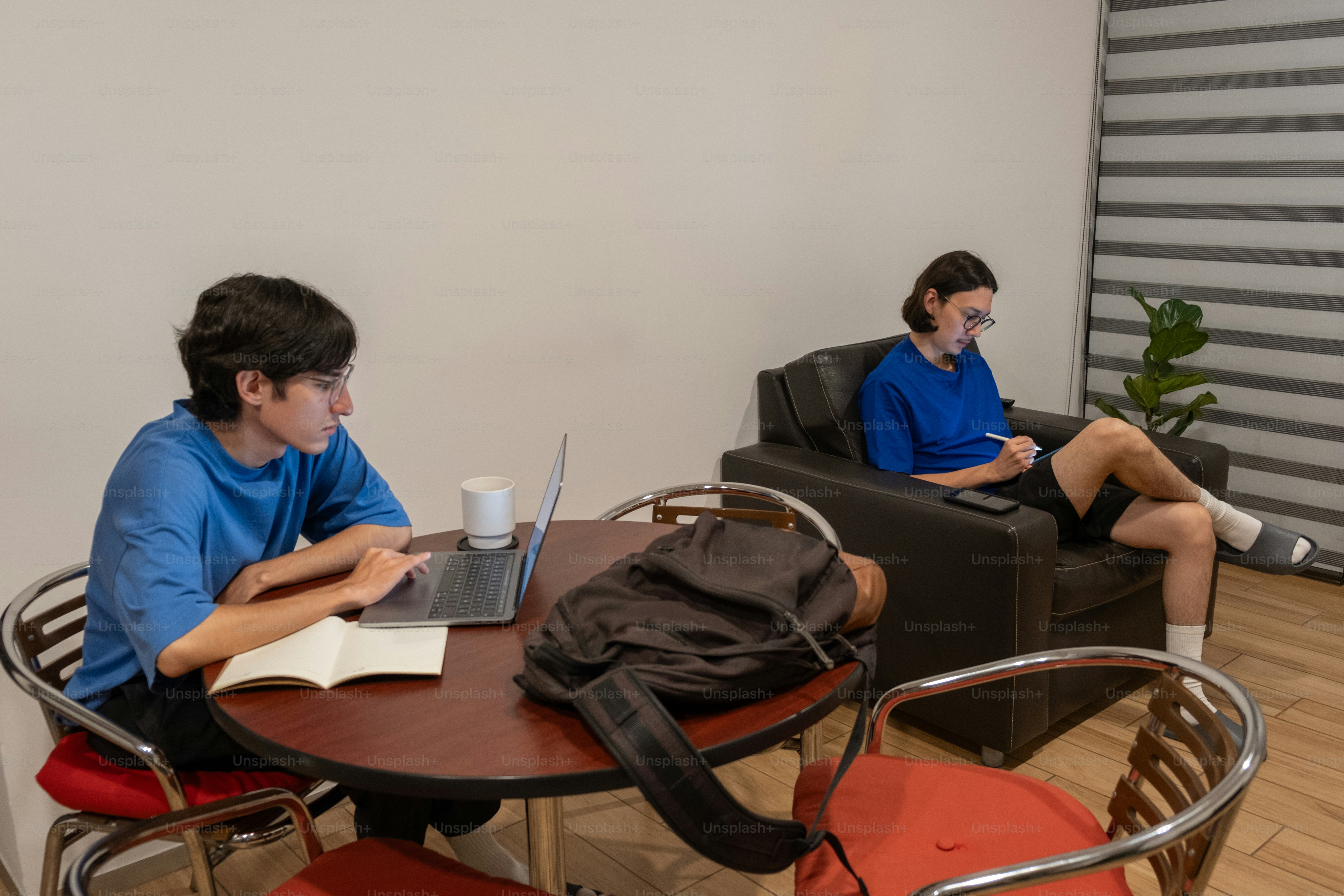 Two men sitting at a table with laptops