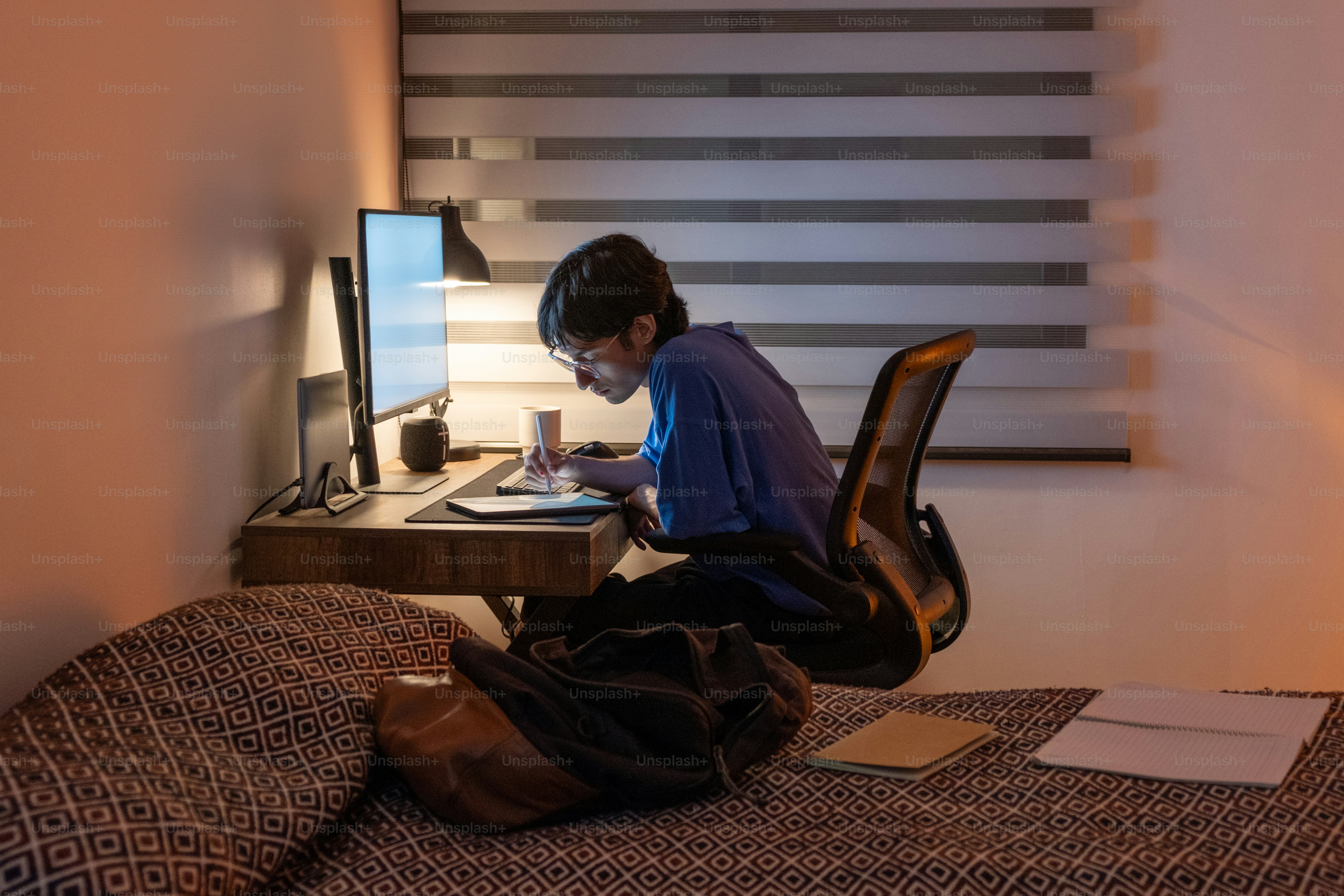 A person sitting on a bed looking at a laptop
