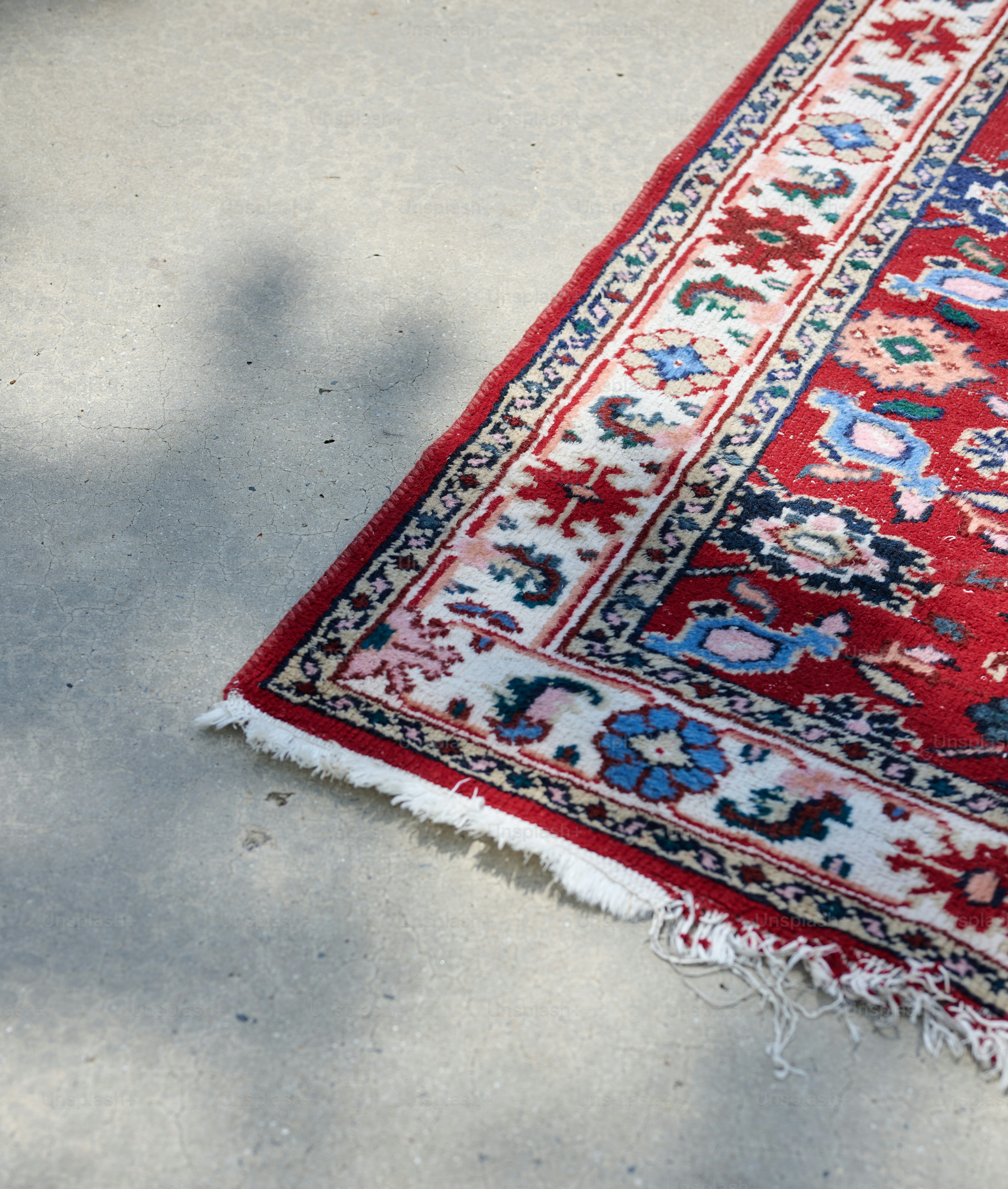 A red rug laying on the ground with a shadow on it