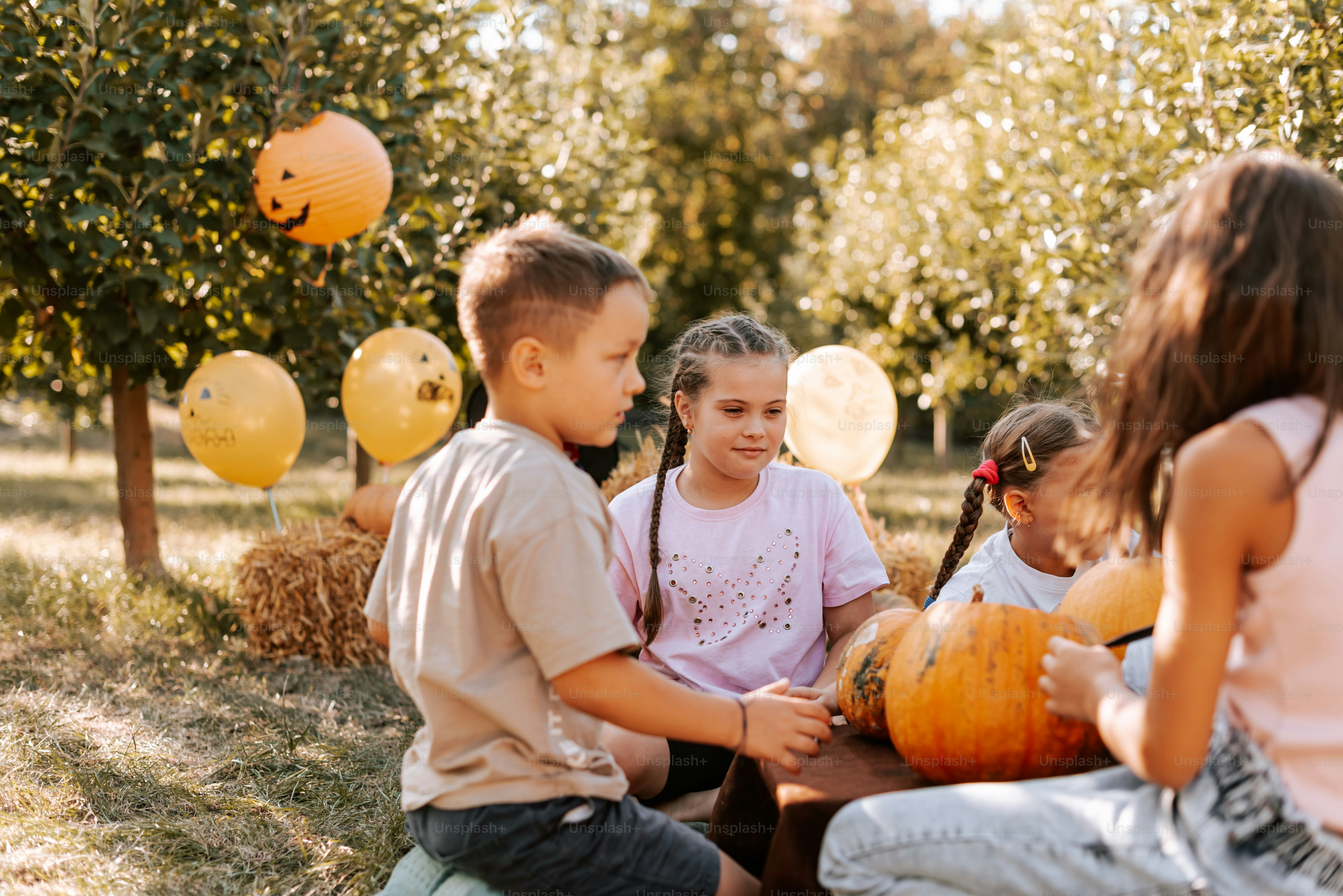 A group of children sitting around a table with pumpkins photo ...