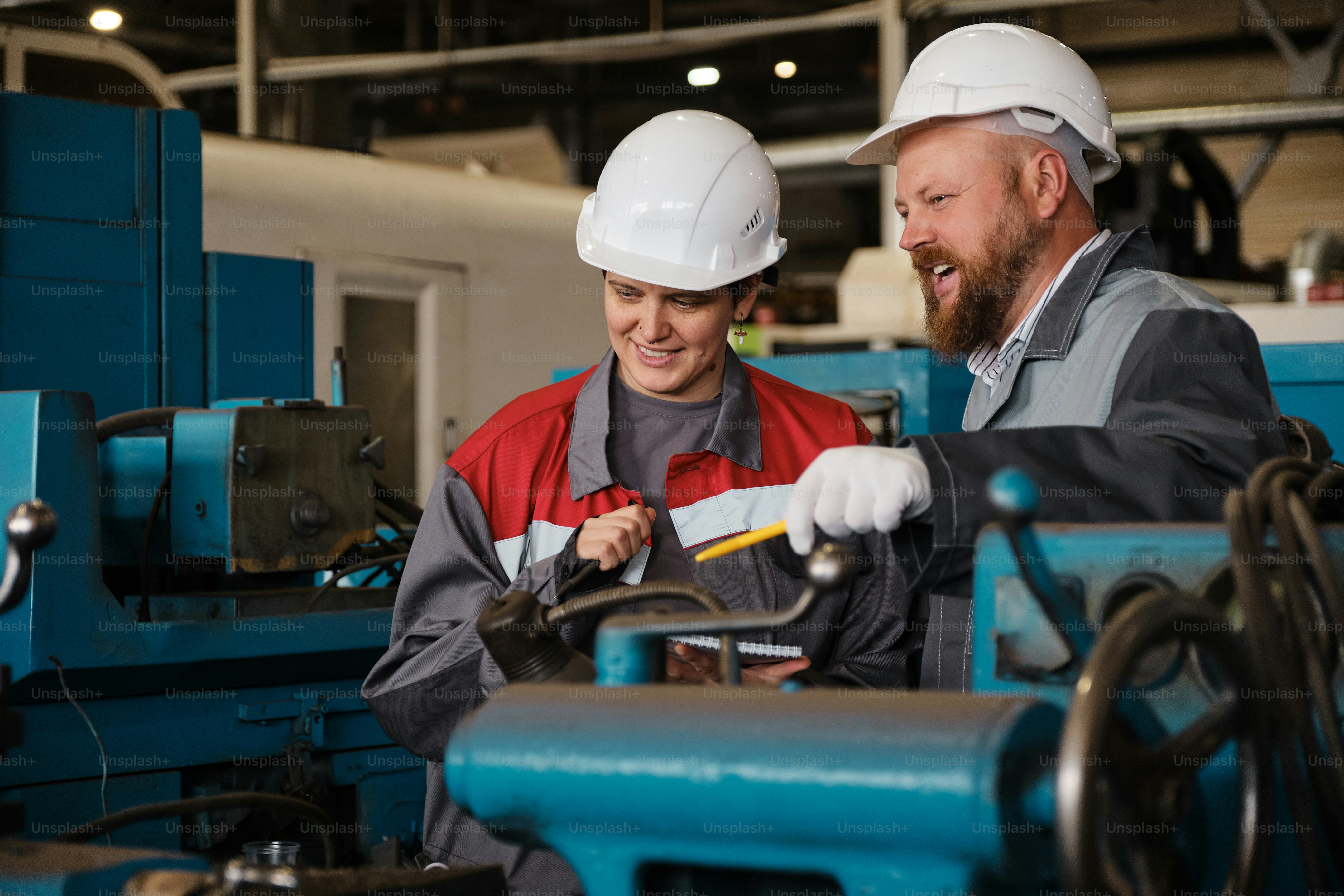 A man and a woman working on machinery in a factory