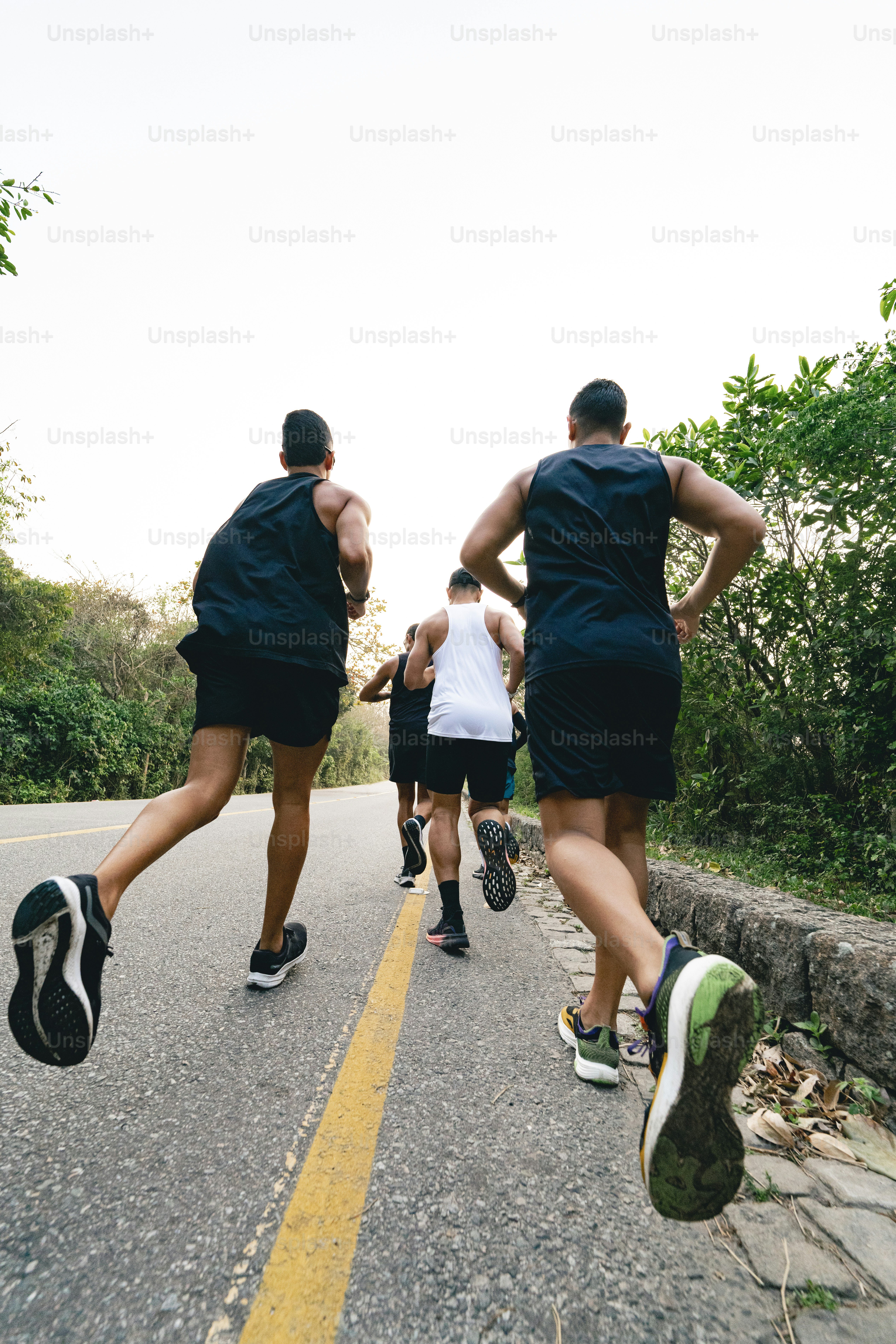 A group of men running down a road photo – Fitness Image on Unsplash