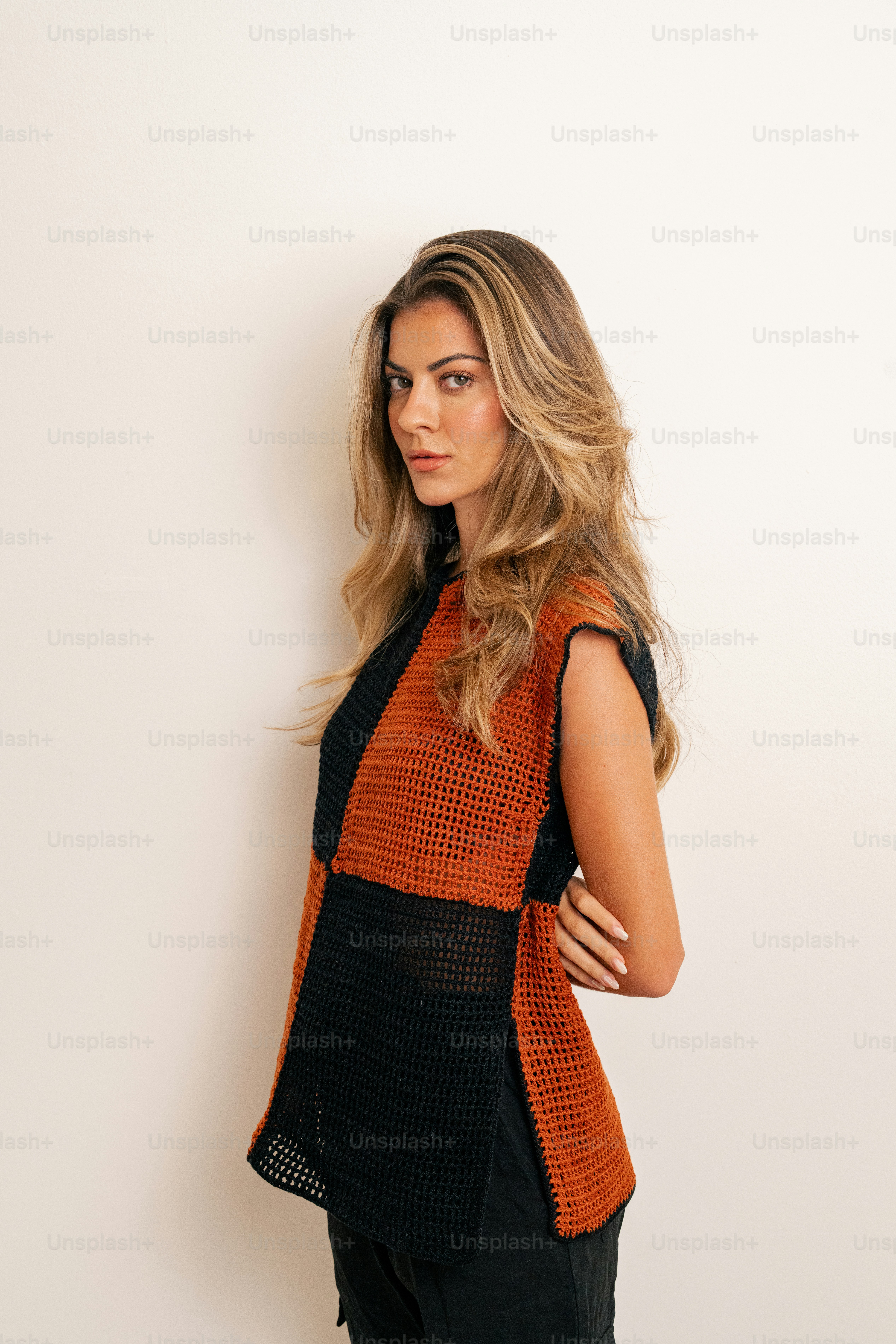 A woman is posing for a picture in a black and orange top