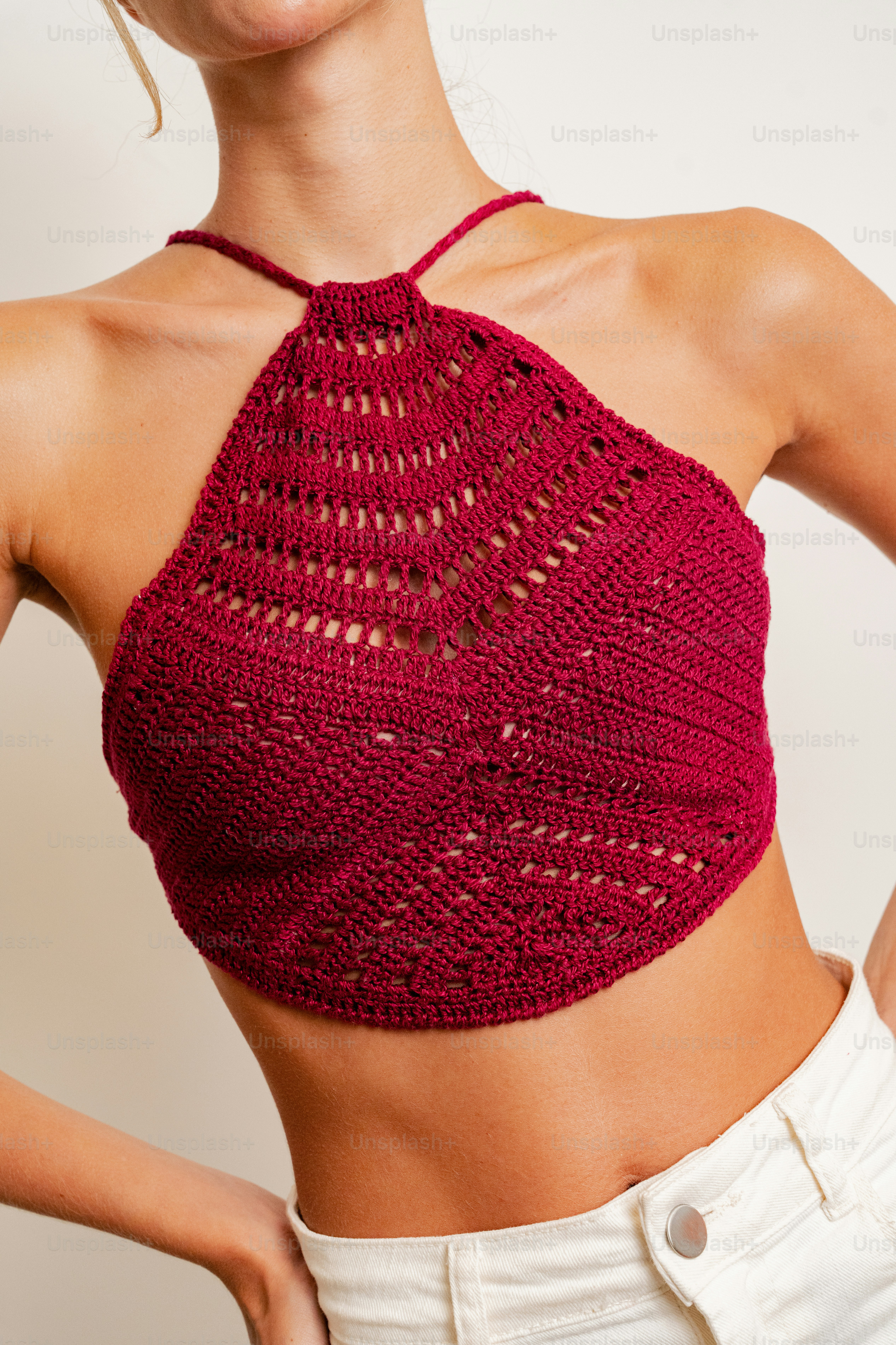 A woman wearing a crochet top and white pants