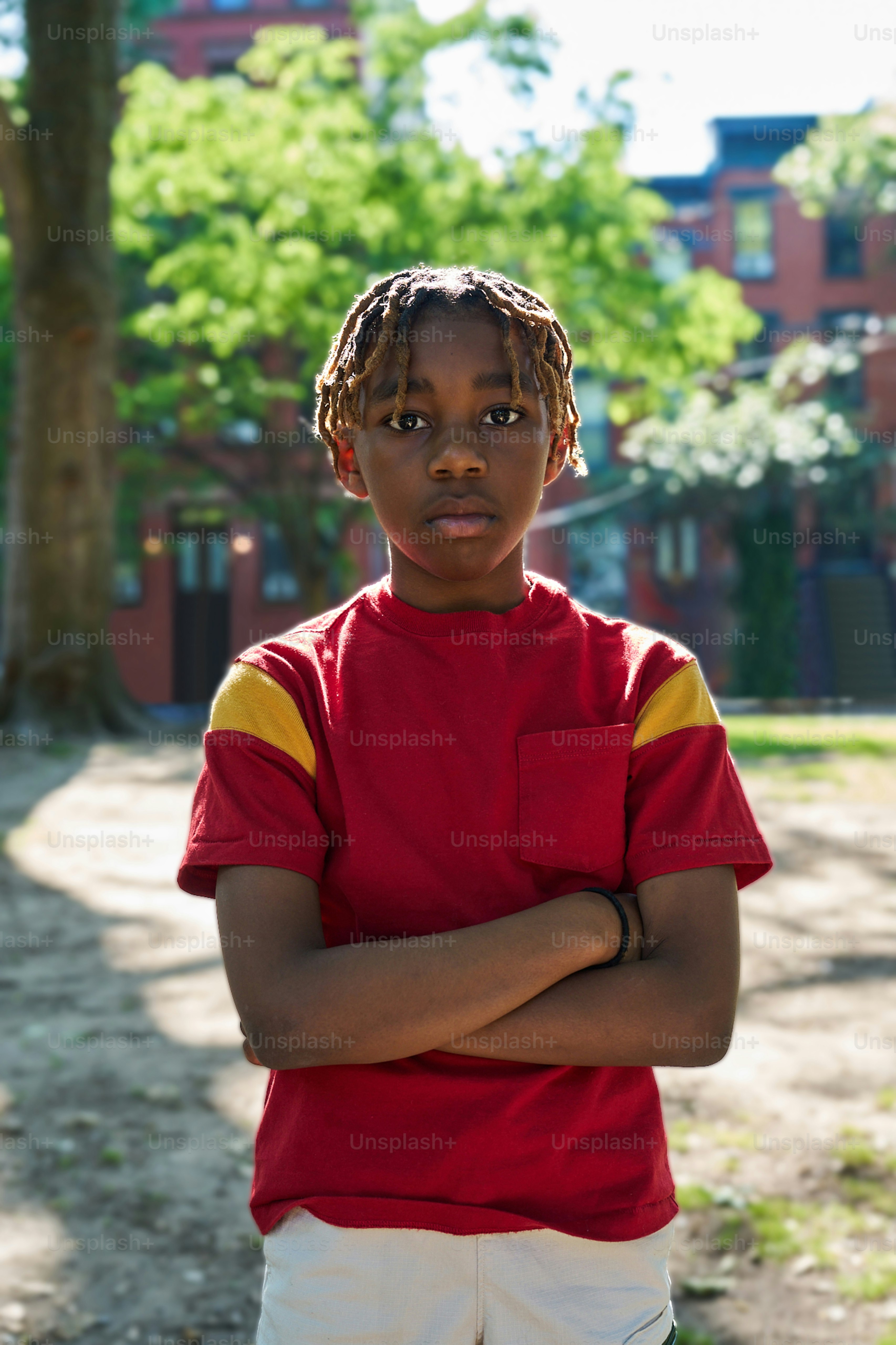 A boy in a red shirt is standing with his arms crossed