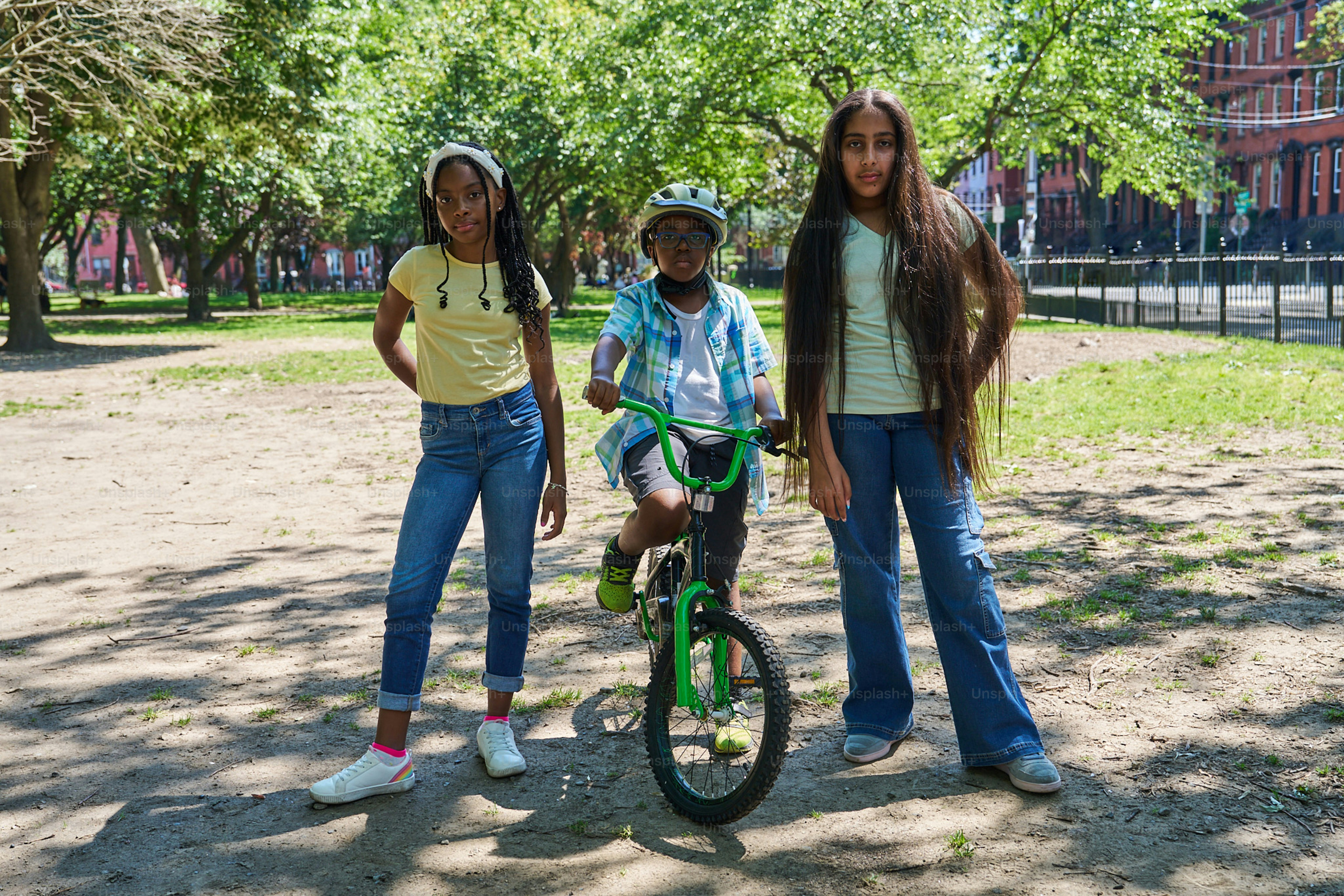 Three girls standing next to a boy on a bike