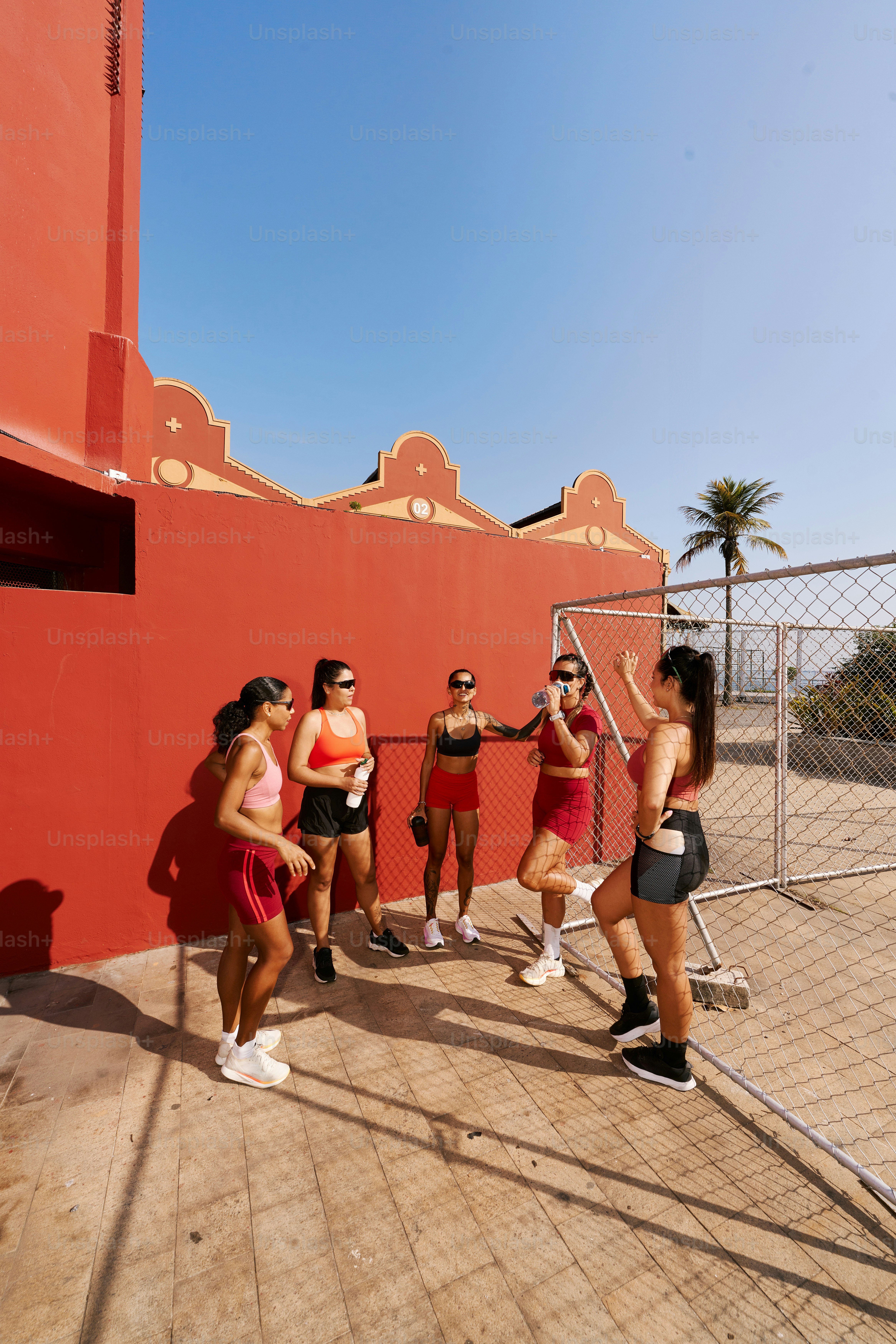 A group of women standing next to each other near a fence