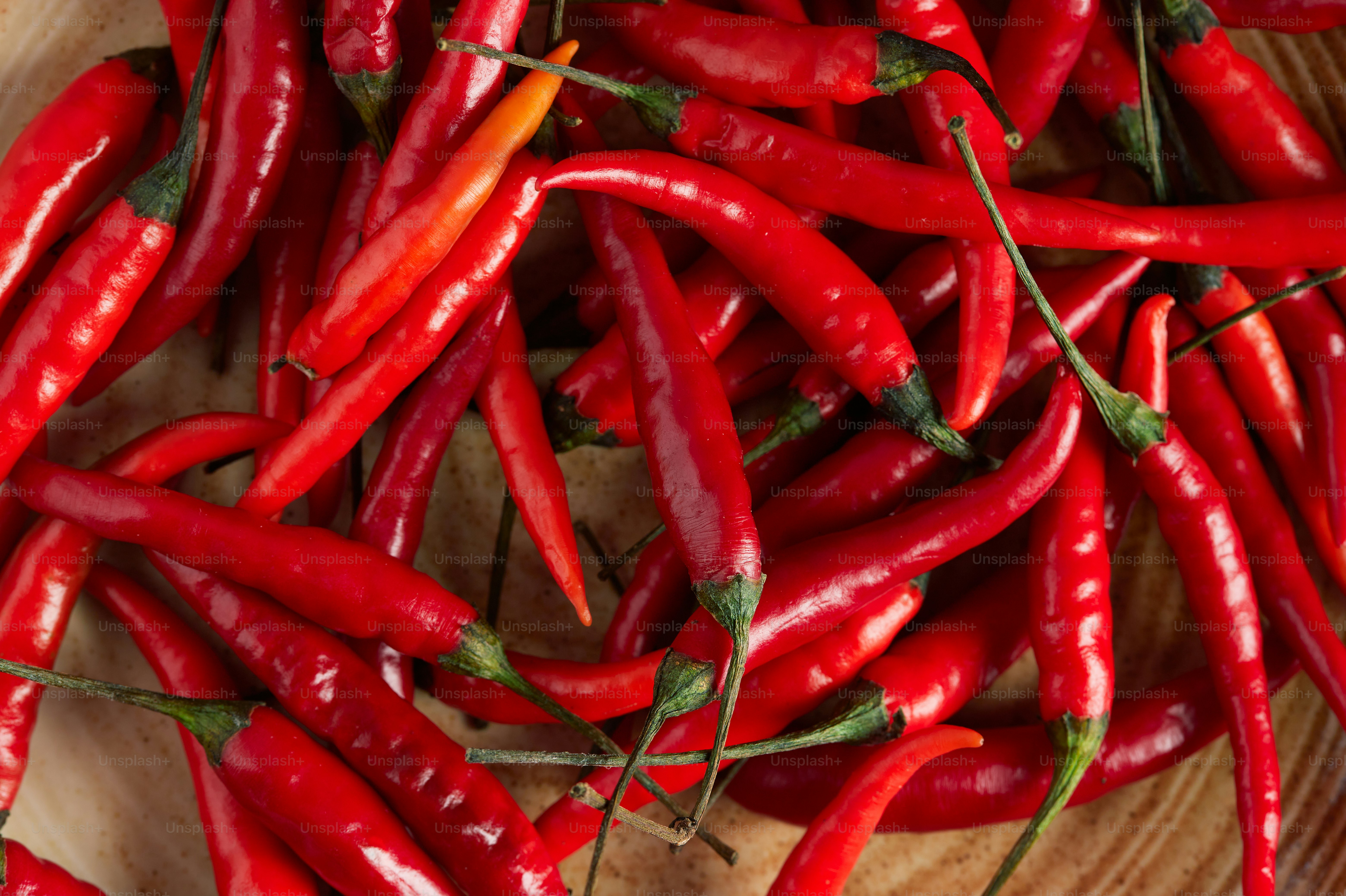 A pile of red peppers sitting on top of a wooden cutting board