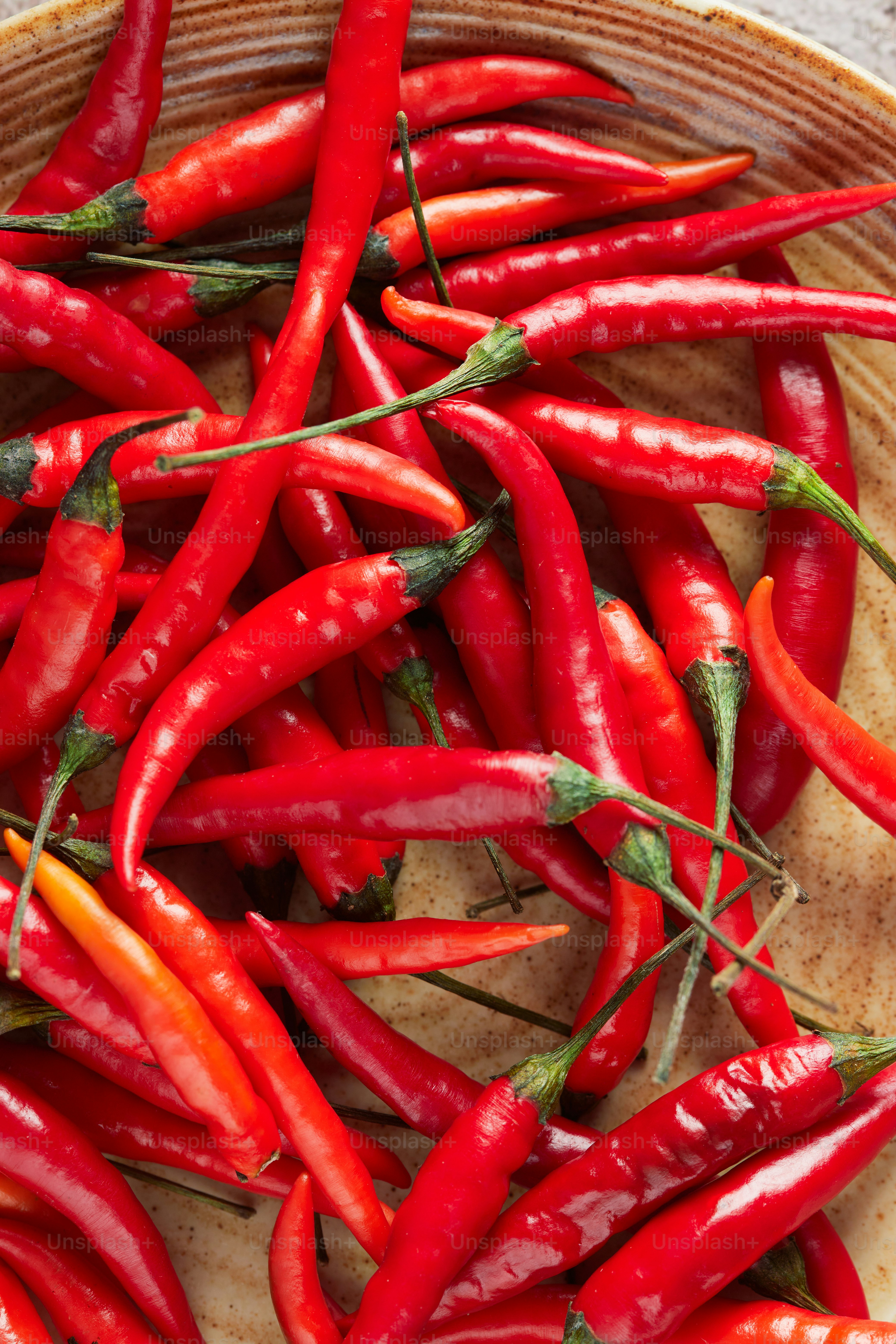 A wooden bowl filled with red peppers on top of a table