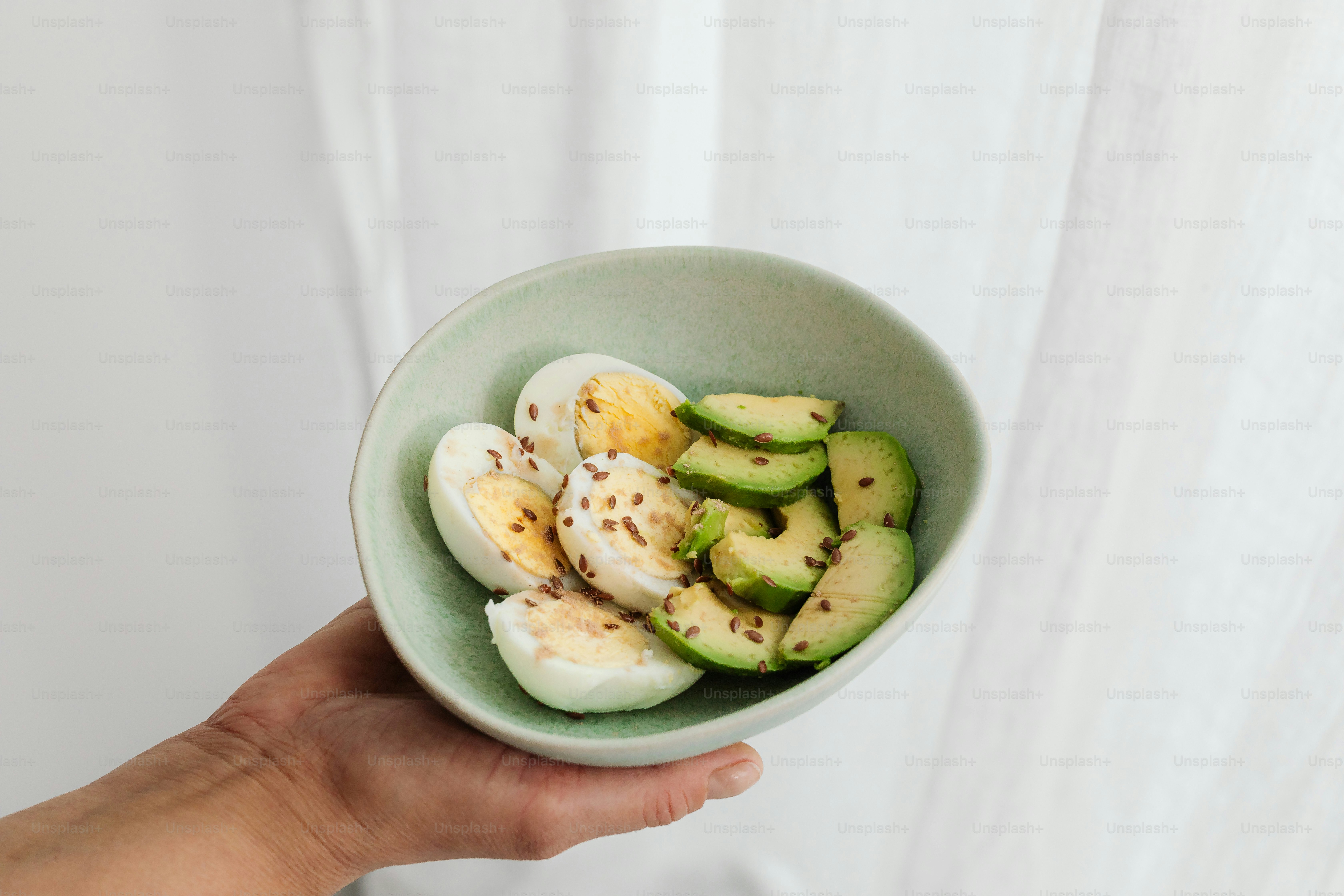 A person holding a bowl of sliced fruit