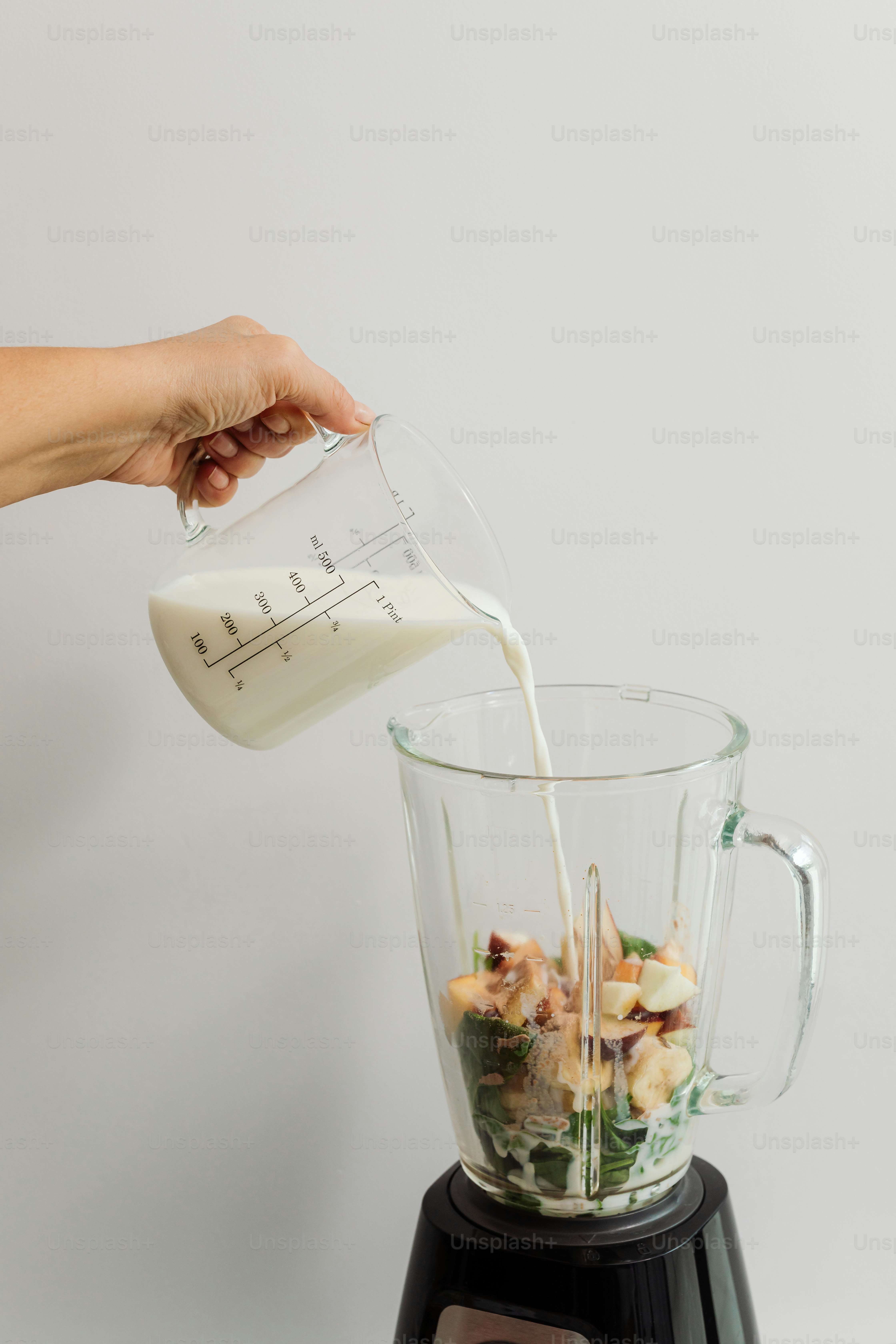 A person pouring milk into a blender