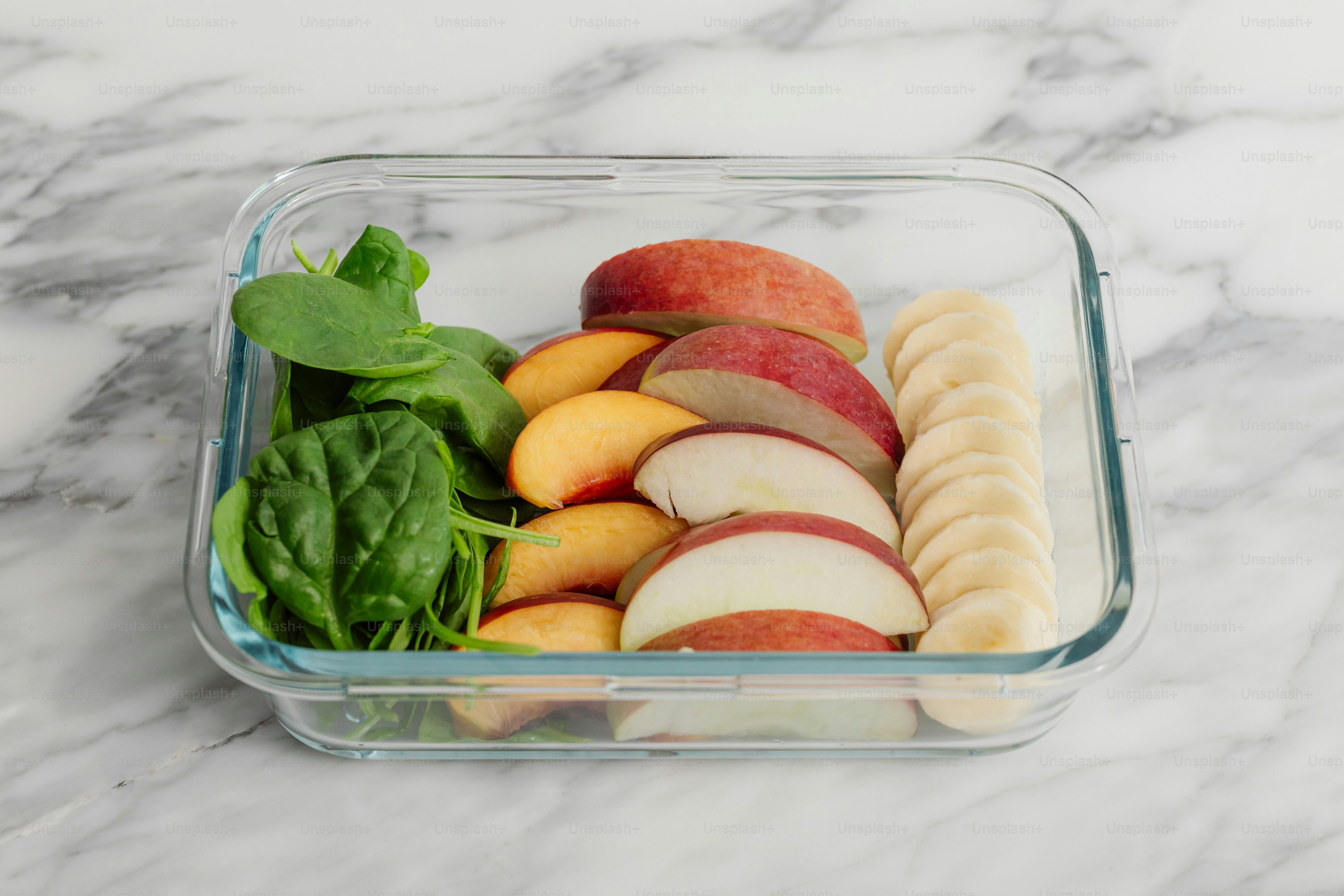 Um recipiente de vidro cheio de frutas em cima de um balcão de mármore
