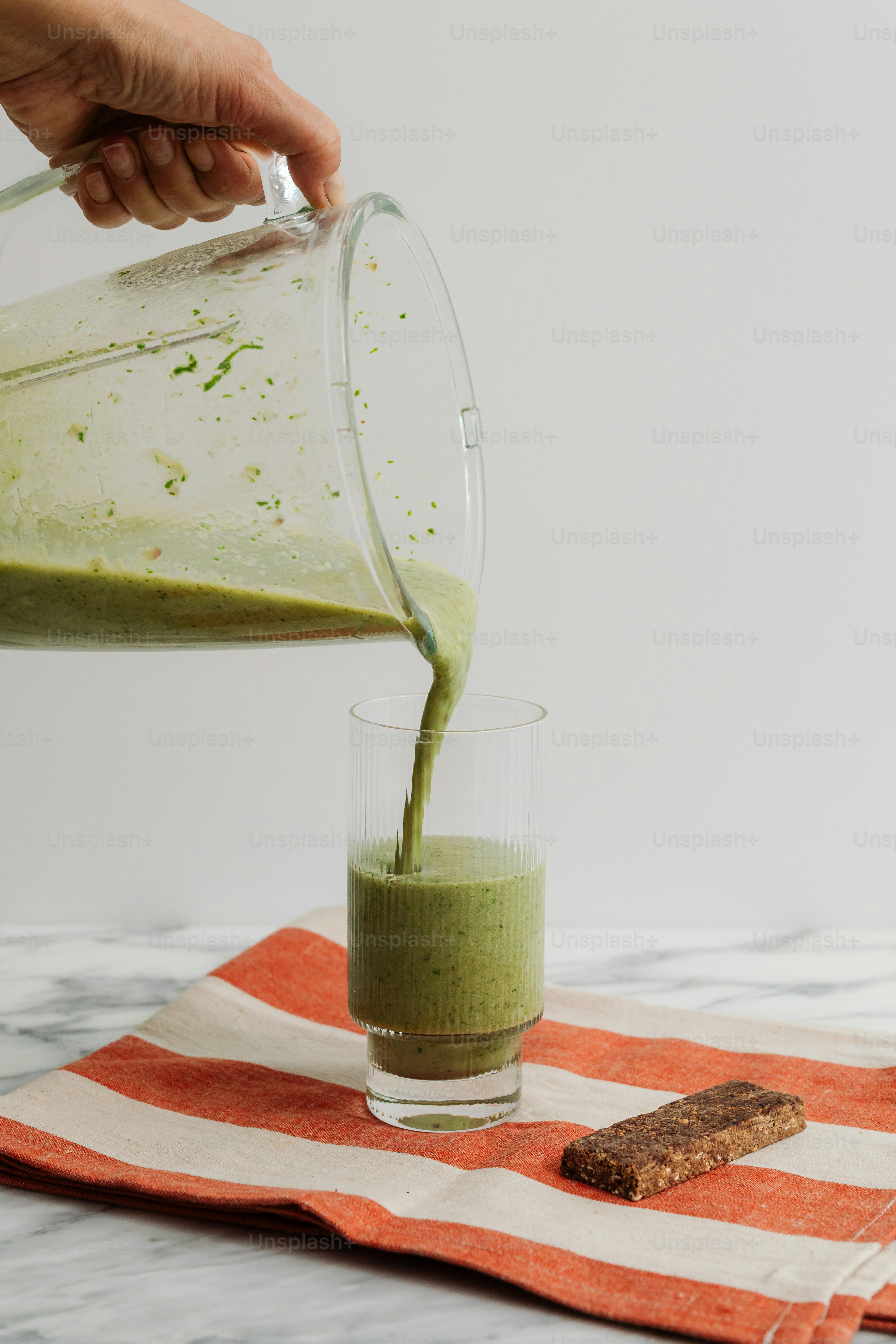 A person pouring a green drink into a glass