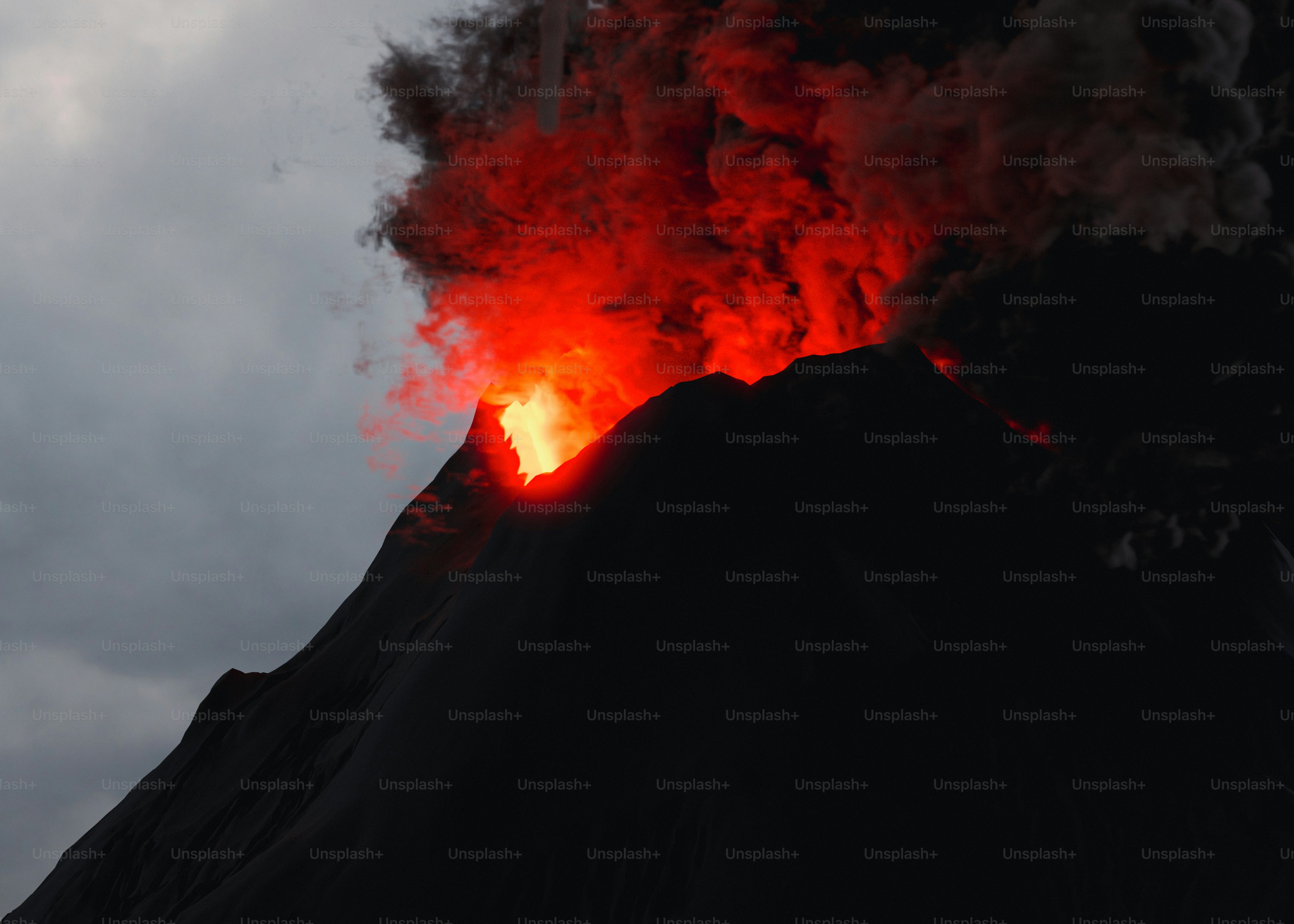 A volcano erupts red smoke as it erupts into the sky