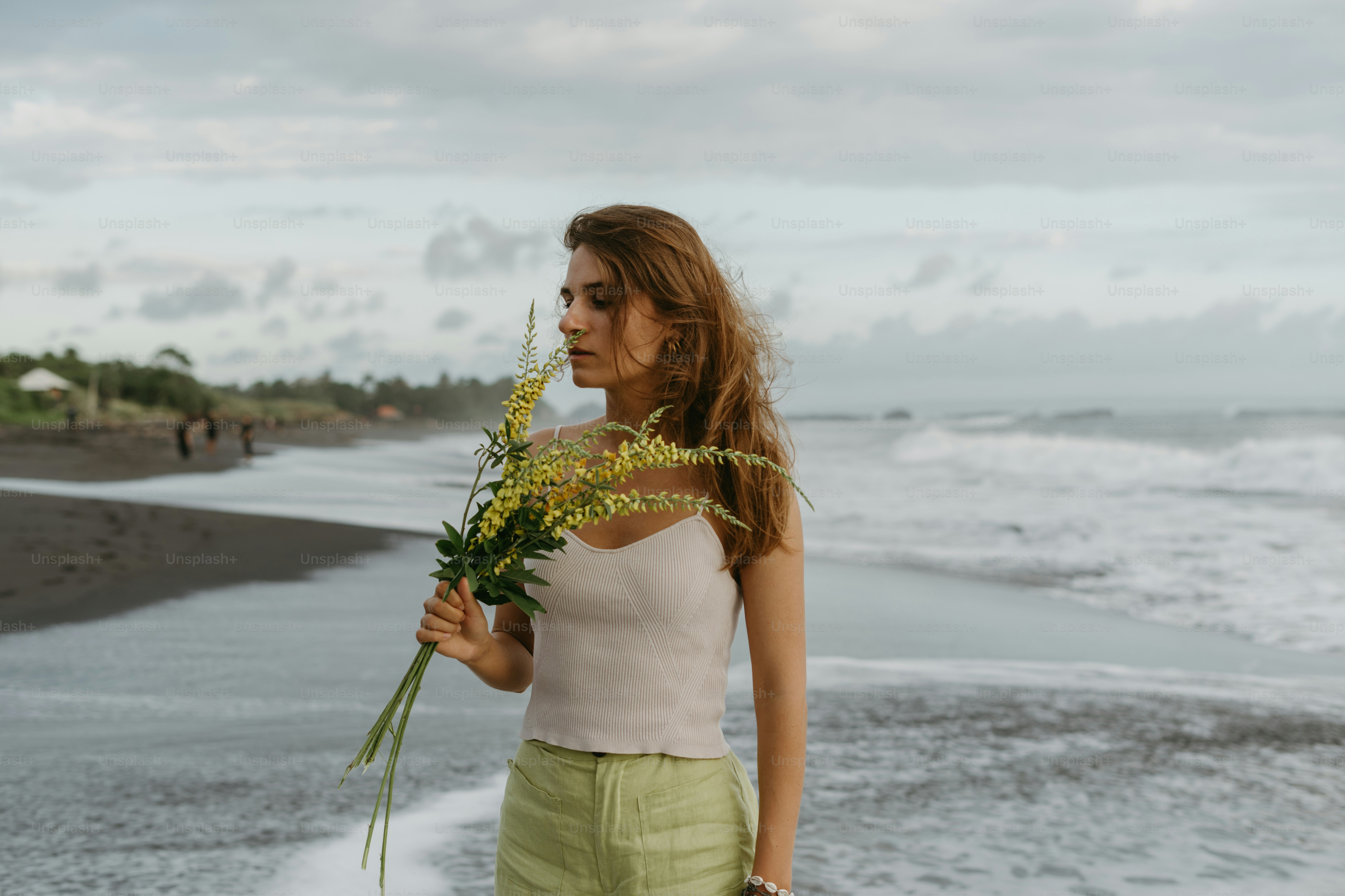Una mujer de pie en una playa sosteniendo un ramo de flores