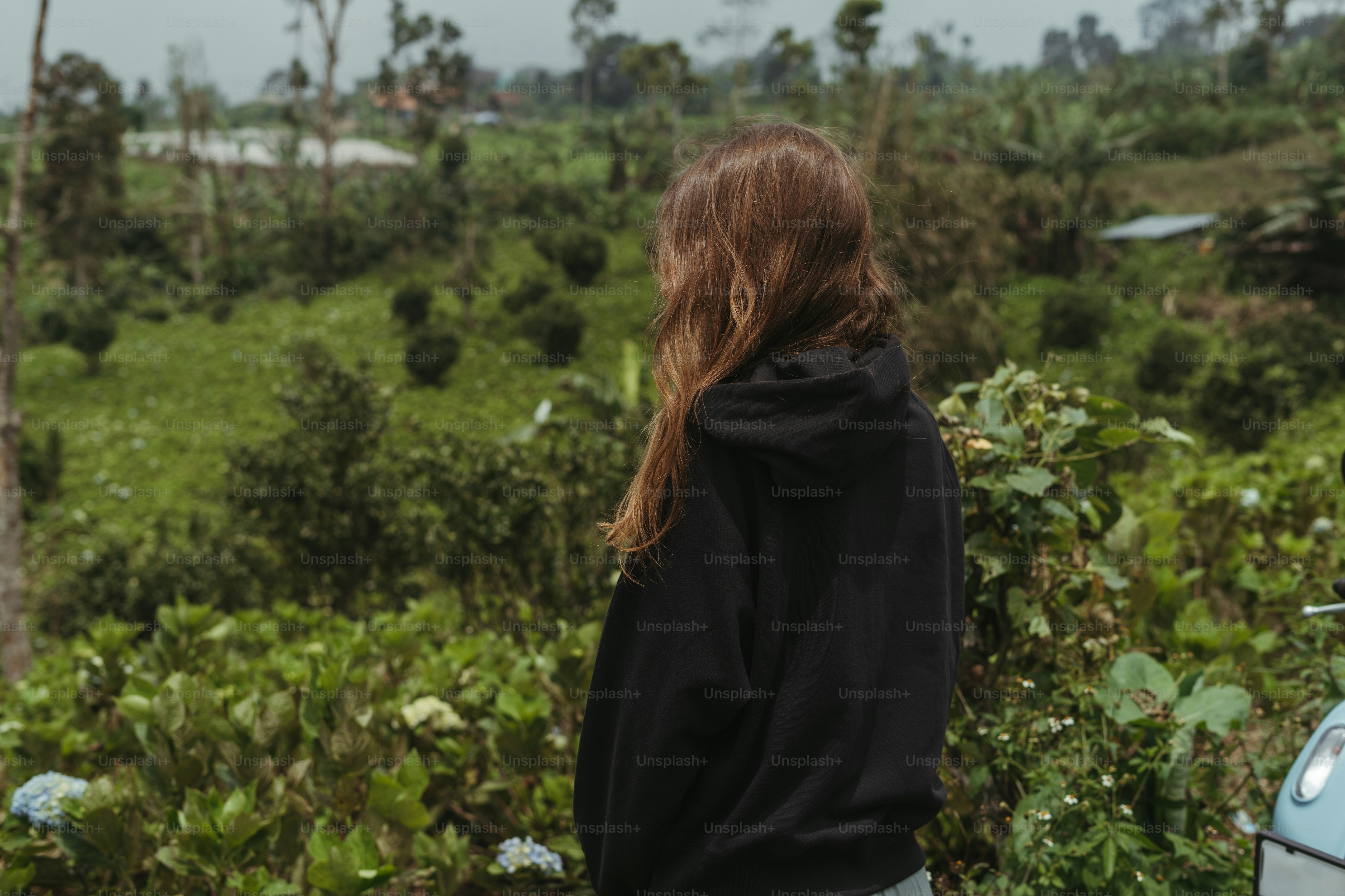 A woman standing in front of a blue car