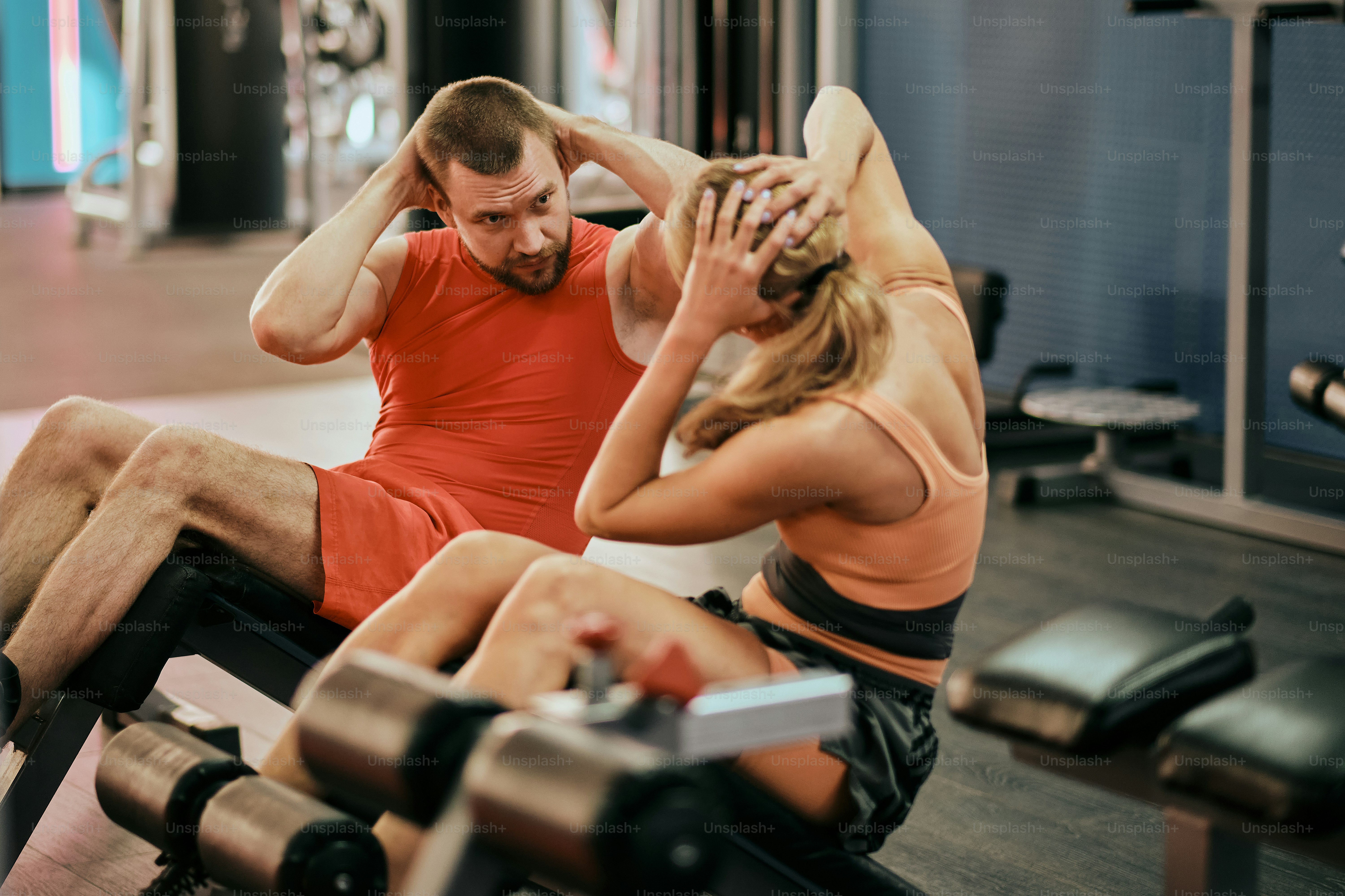 Un hombre y una mujer sentados en un banco en un gimnasio