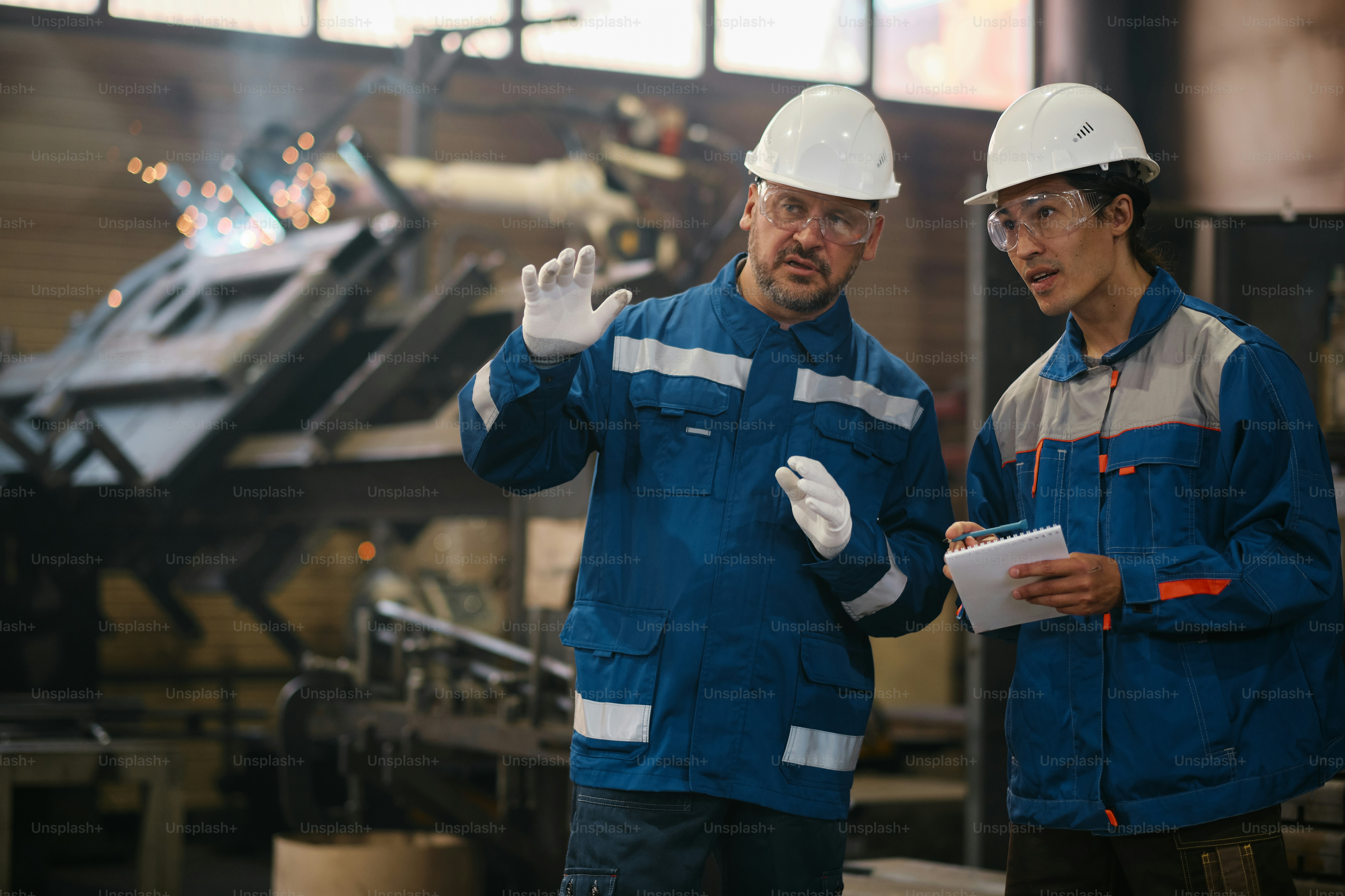 Two men in hardhats standing in a factory
