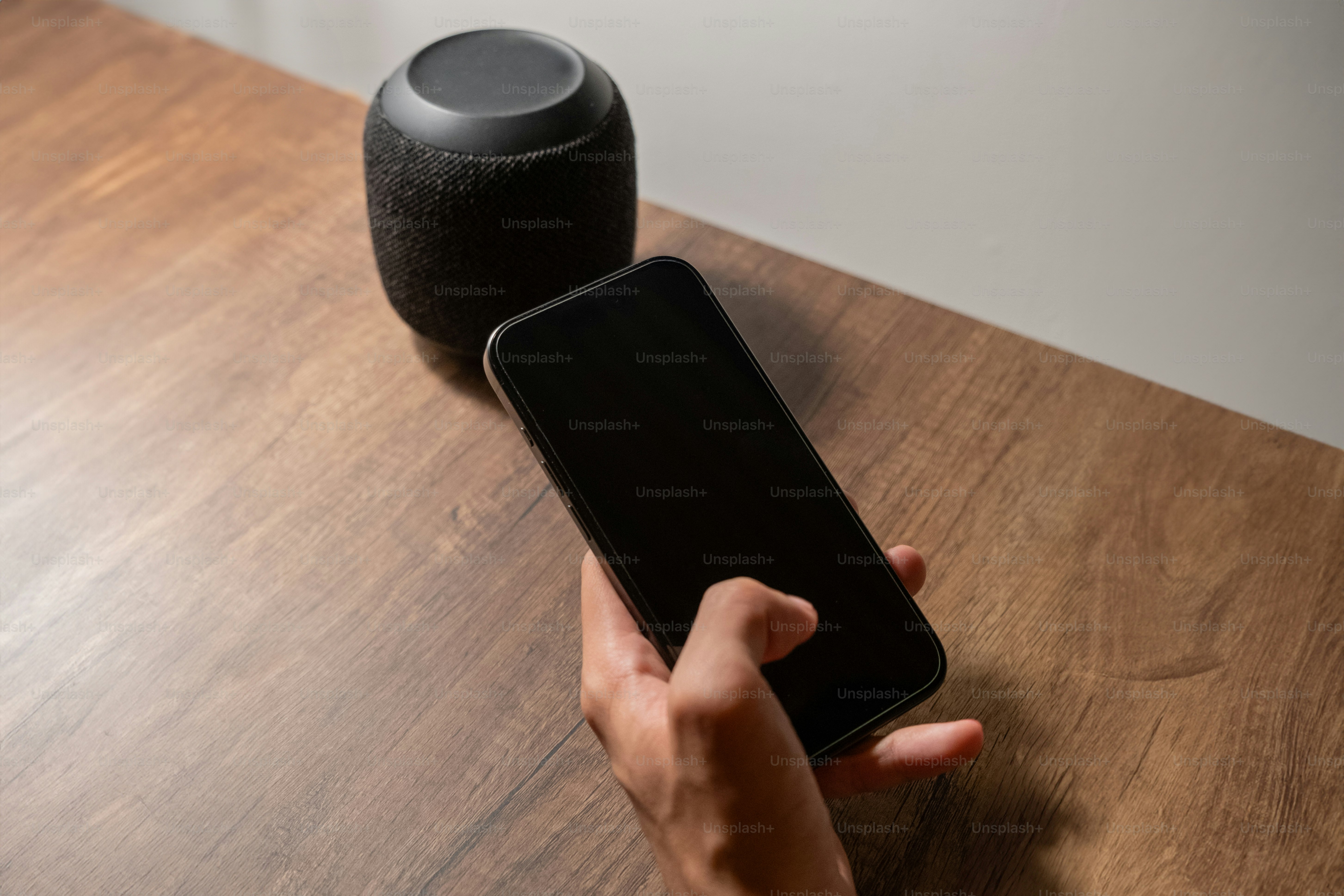 A person holding a cell phone next to a speaker